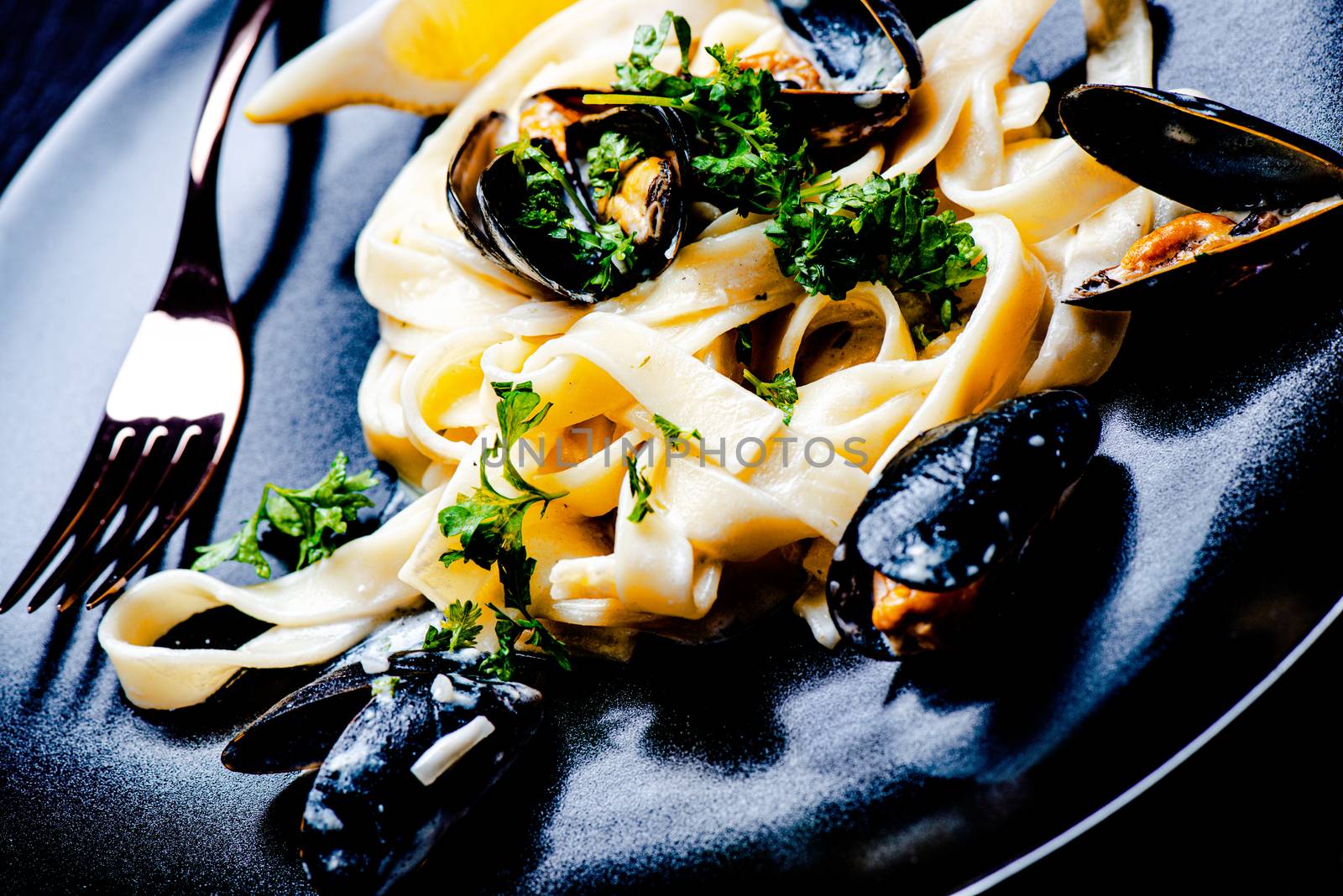 Blue mussels and pasta in black plate by Nanisimova