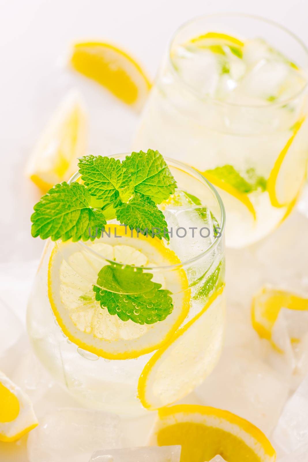 Lemonade drink in a glass: water, ice, lemon slice and mint