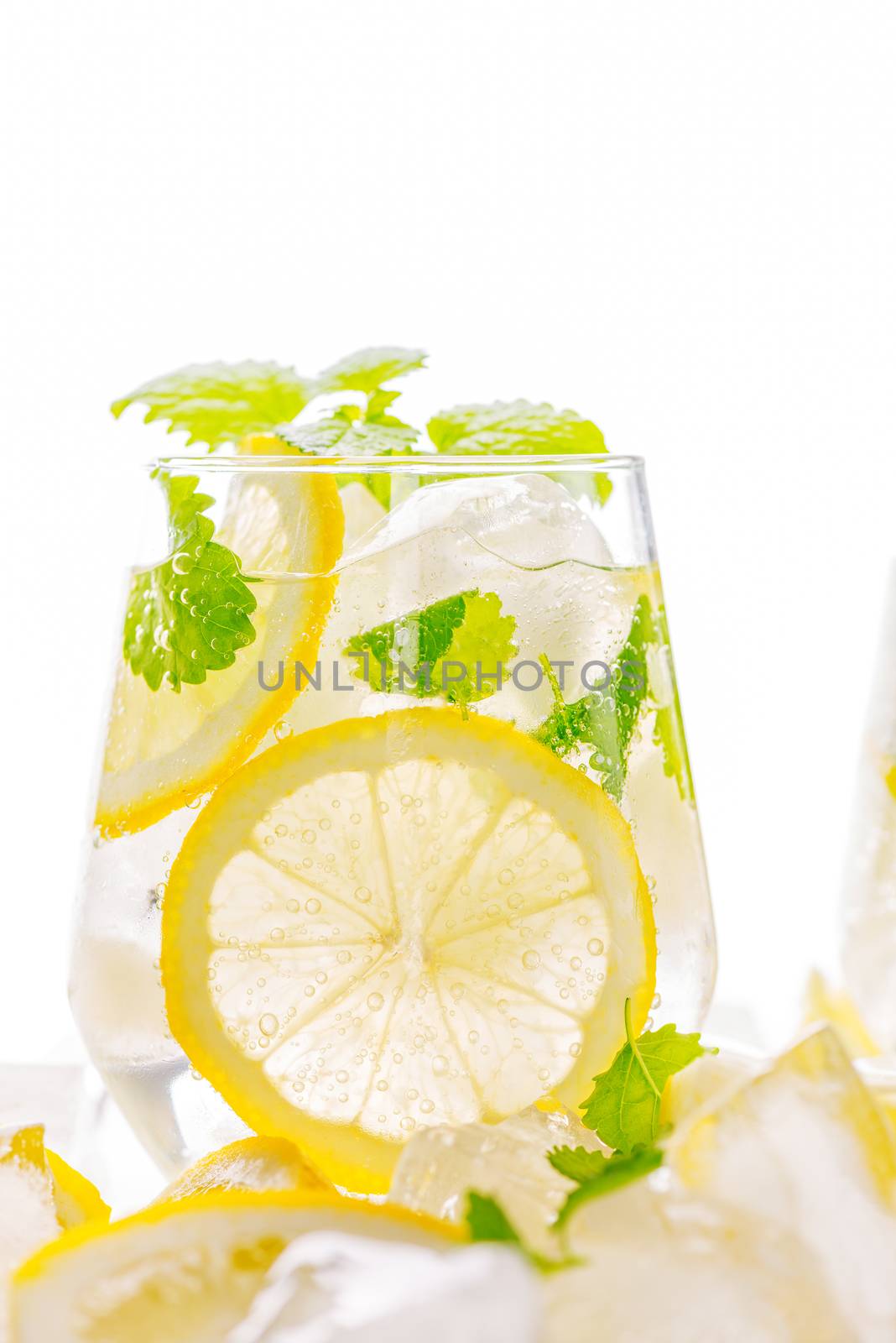 Lemonade drink in a glass: water, ice, lemon slice and mint on white background