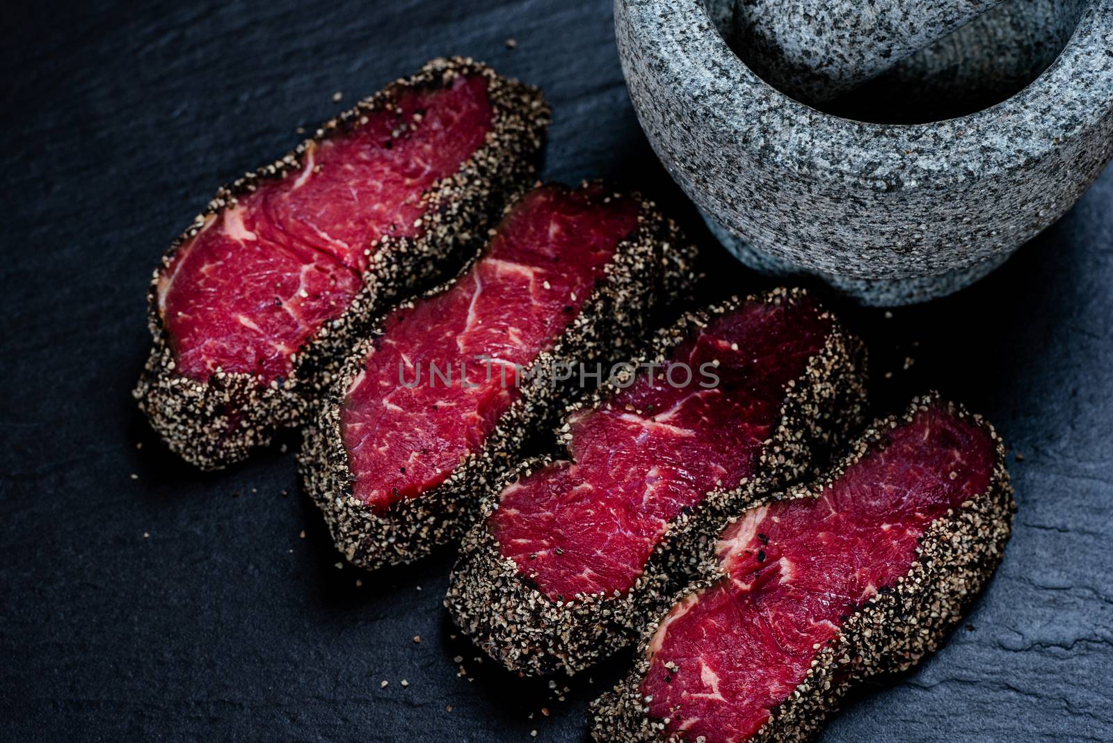 Pepper steaks on stone with mortar bowl and pestle