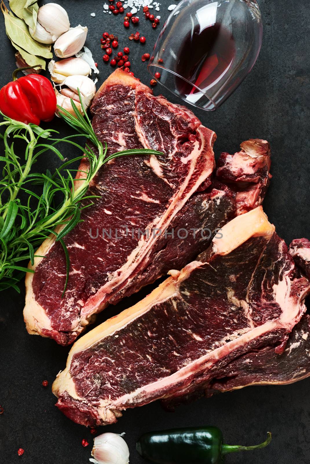 Raw aged steak and seasoning on dark background by Nanisimova