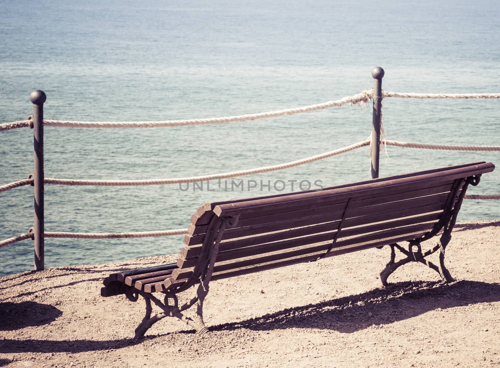 Empty wooden bench on the beach. Concept of loneliness, emptiness, solitude.