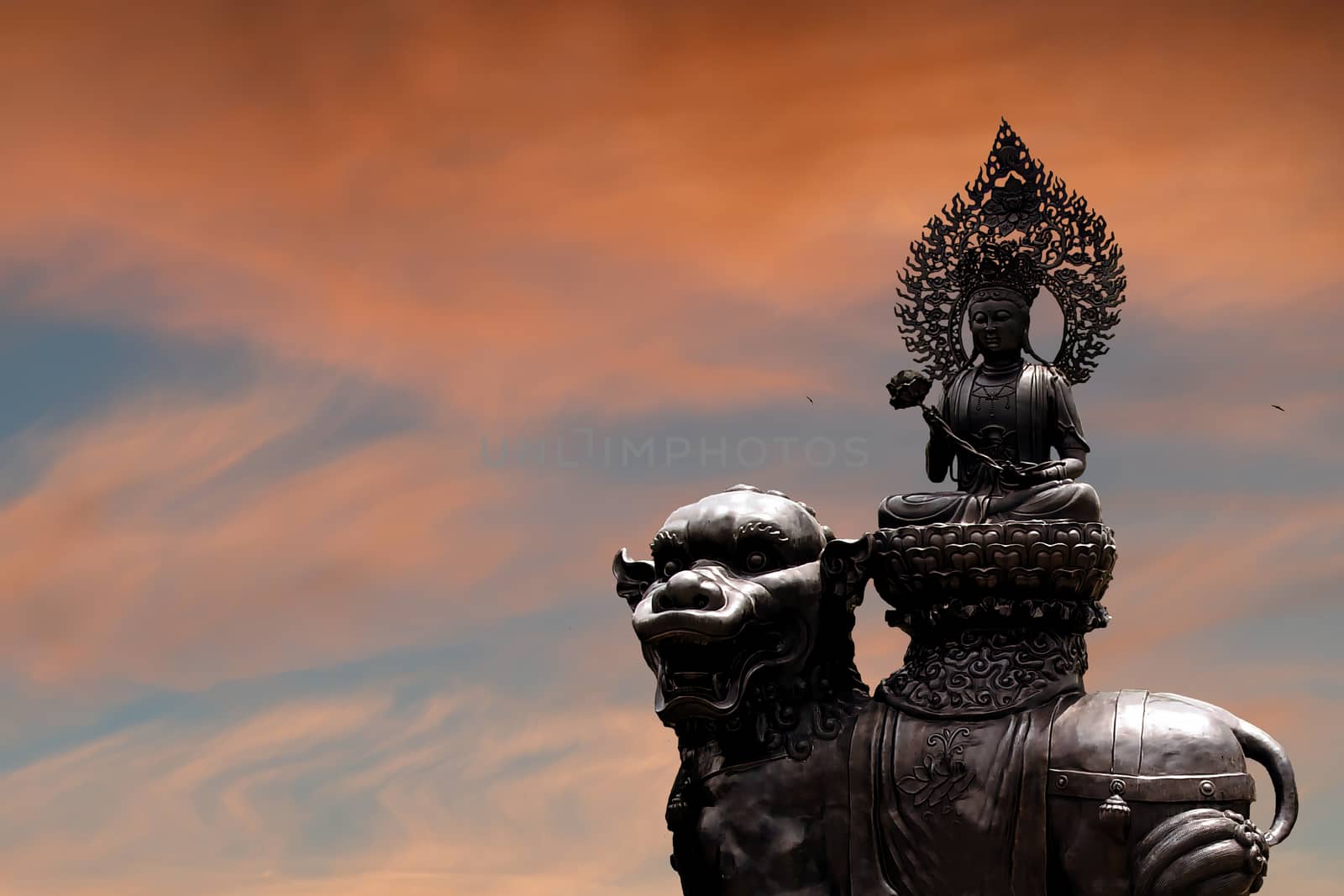 The silhouette of the Buddha statue against the sunset sky. The concept of congratulations from the Buddhist celebration of Buddha's birthday, called Vesak day, Buddhist lent, the Buddha's birthday, the worship of Buddha Purnima. Copy space for your design.
