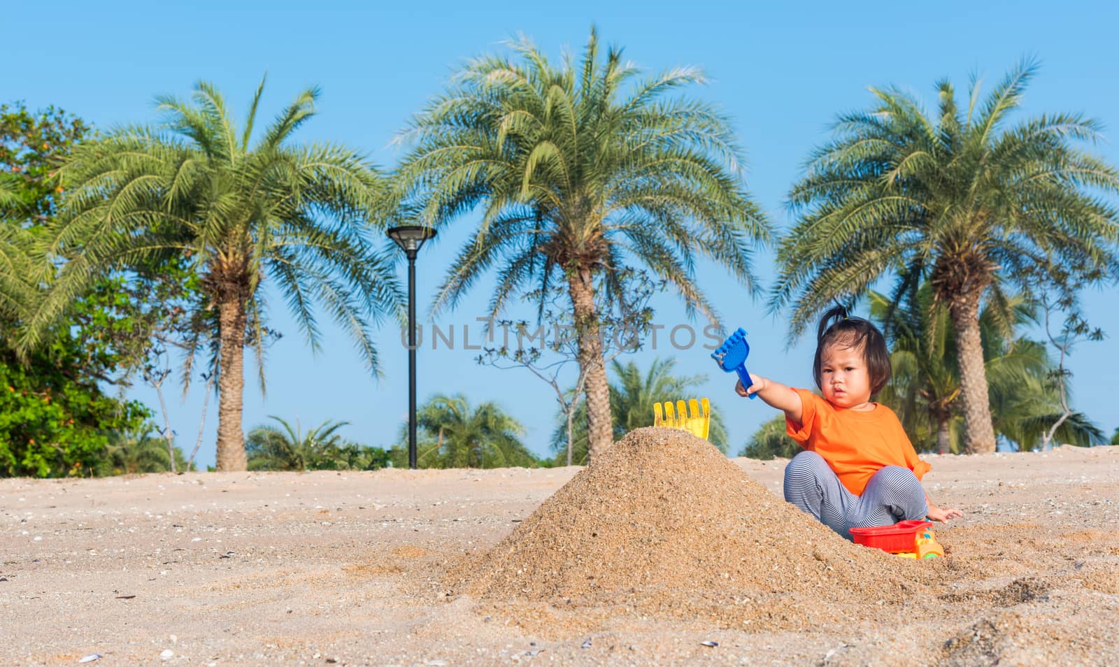 cheerful daughter girl funny digging playing toy with sand by Sorapop
