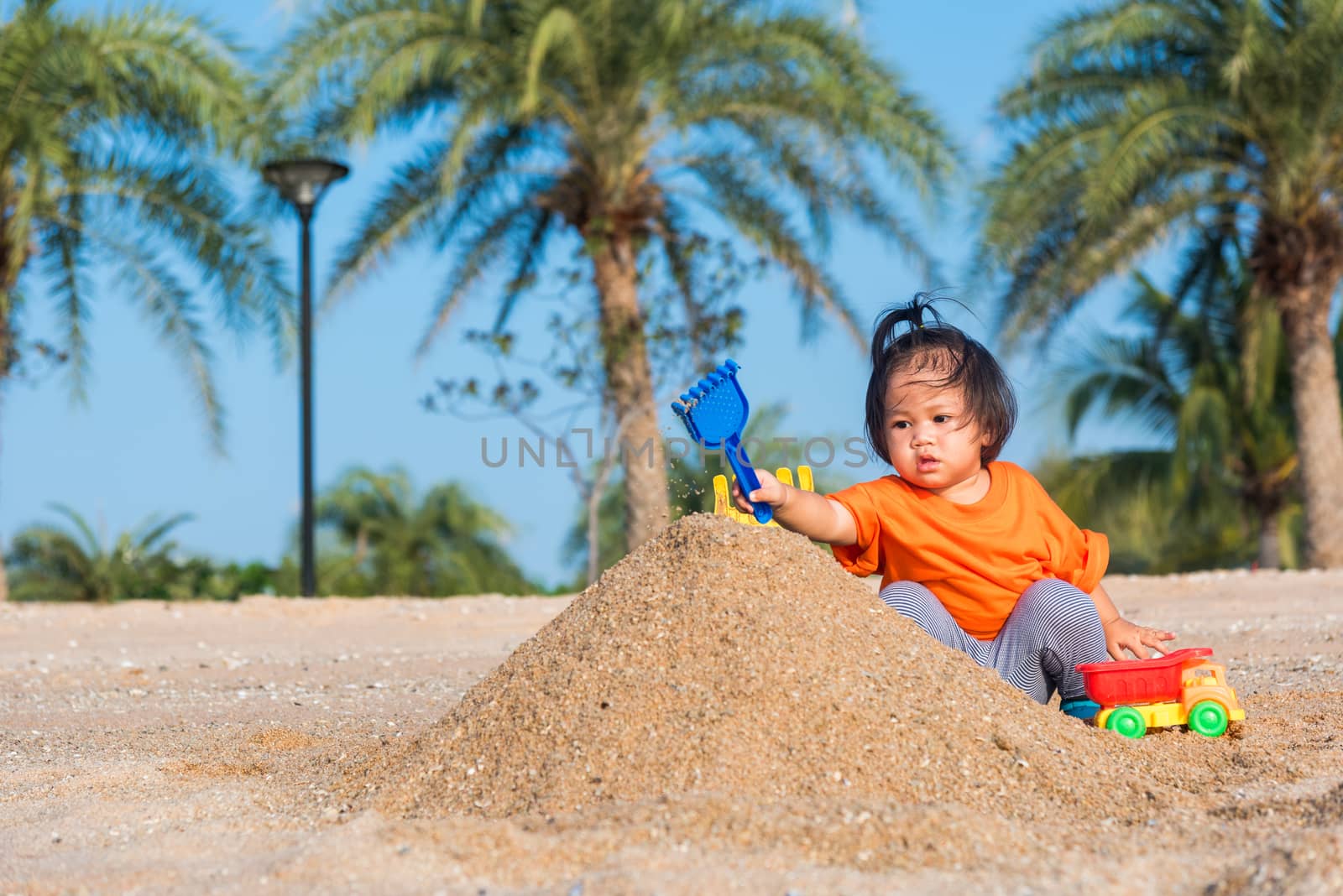 cheerful daughter girl funny digging playing toy with sand by Sorapop