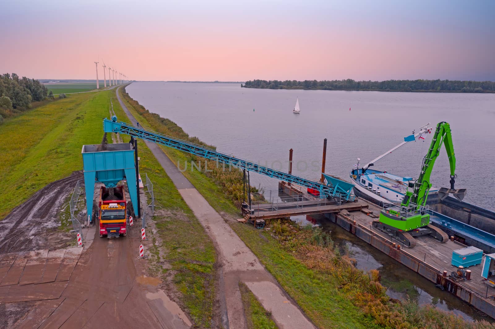 Aerial from freighter unloading sand in the countryside from the Netherlands at sunset