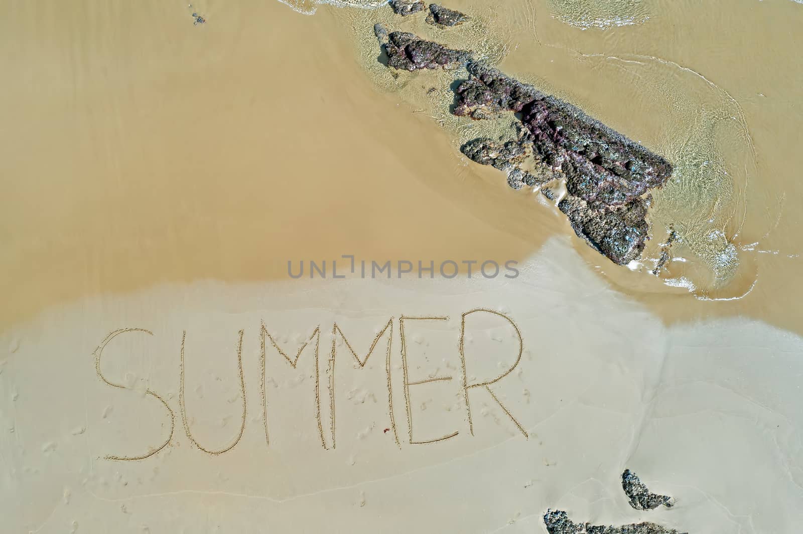 Aerial top shot from ocean waves and handwritten Summer at the beach