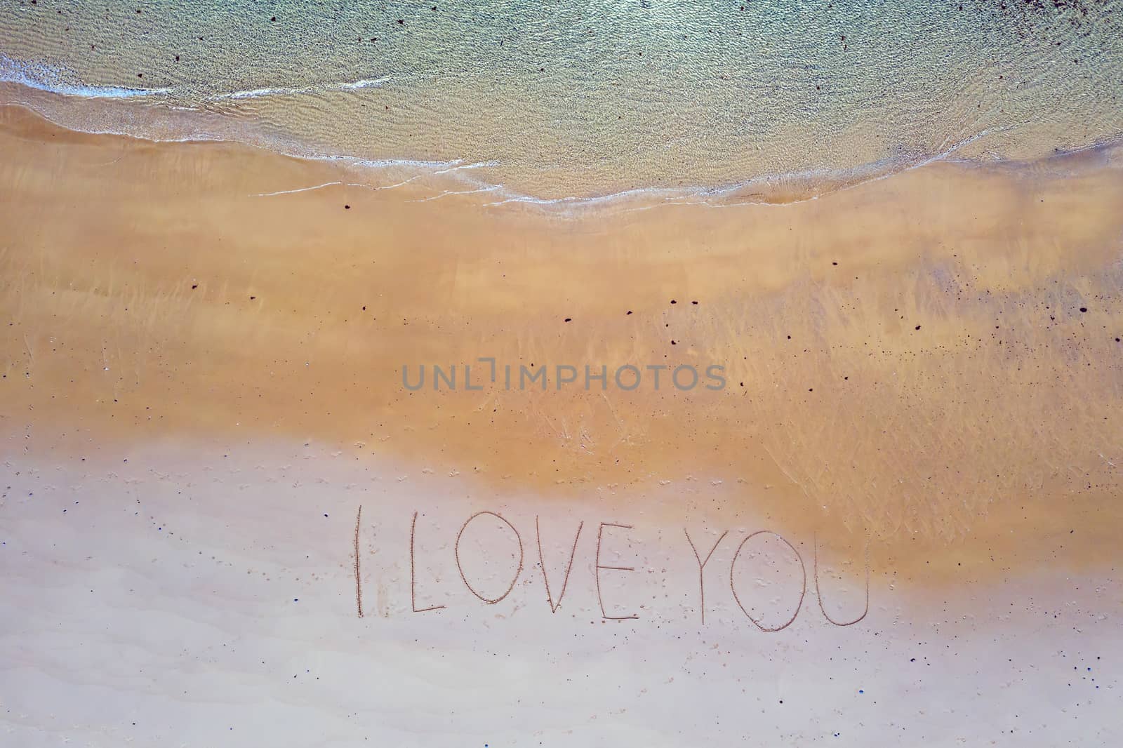 Aerial top shot from ocean waves and handwritten I love you at the beach