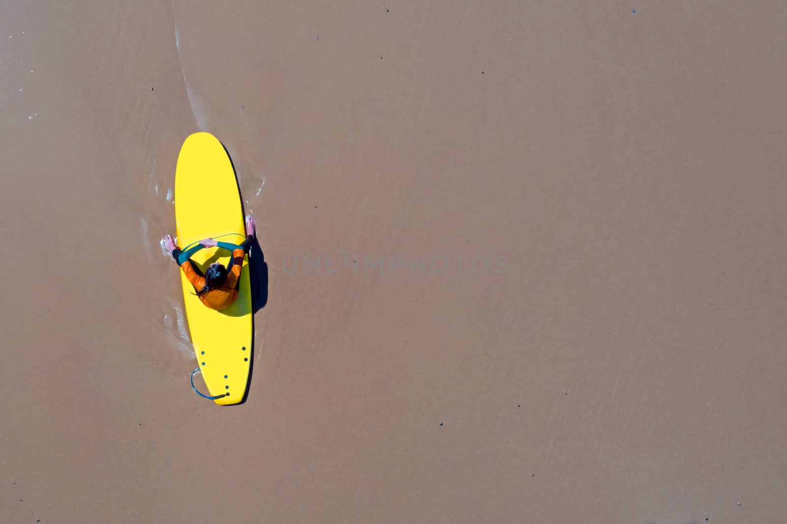 Aerial from a surfer relaxing on her surfboard at the atlantic ocean