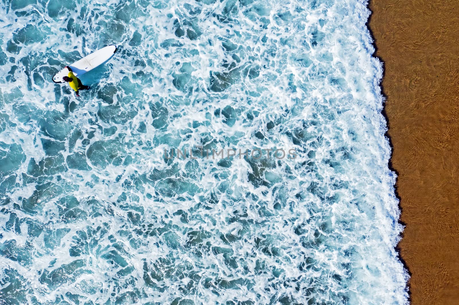 Aerial shot from a surfer going to surf in the ocean