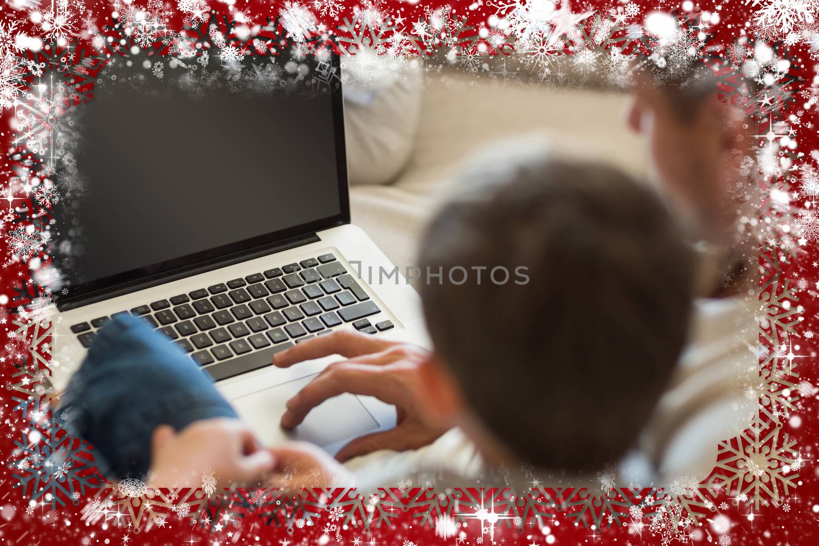 Father and son using laptop in house against snow