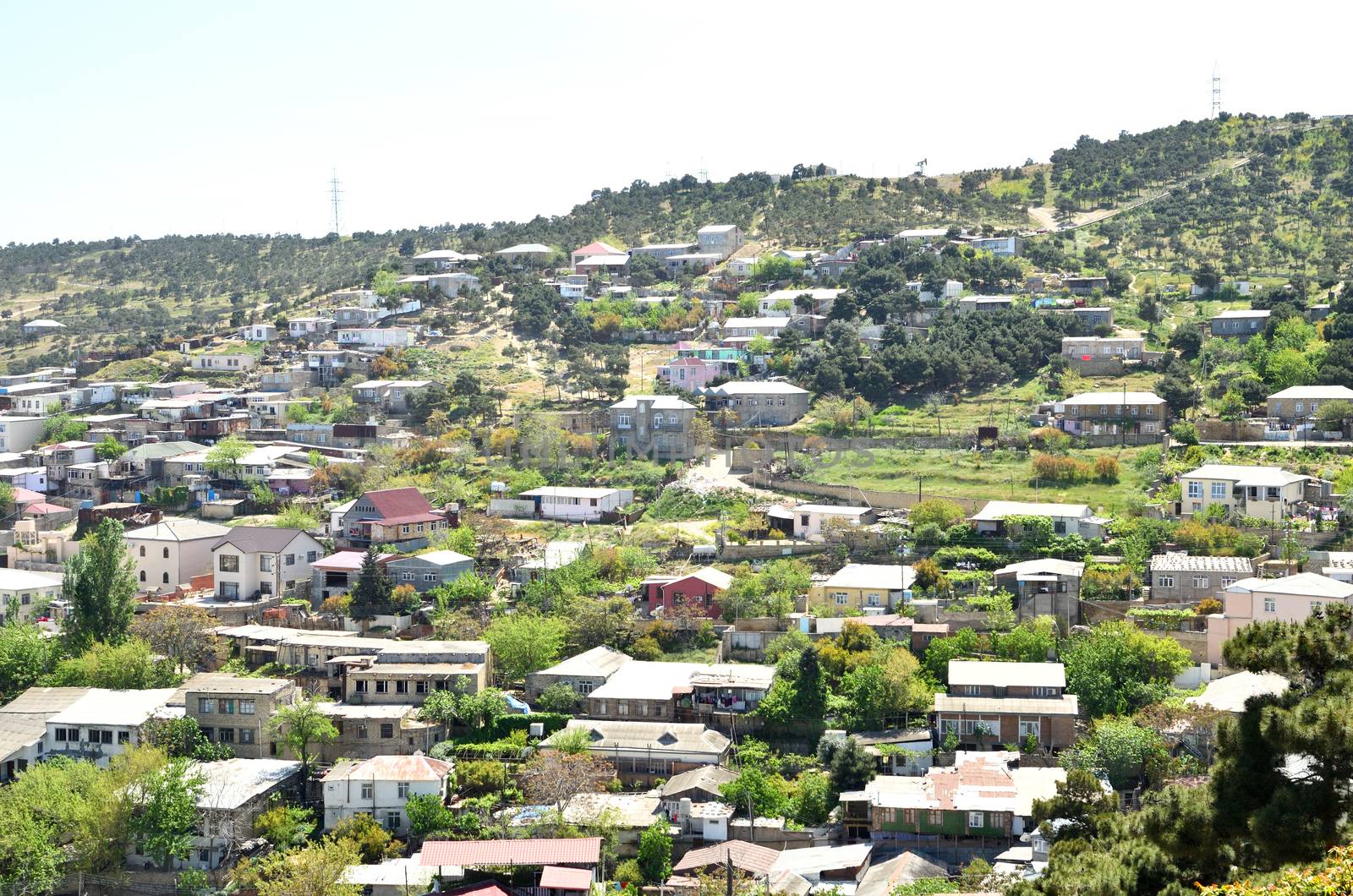 Houses on the slope of the mountain, among the greenery, next to the park on the mountain in Baku.
