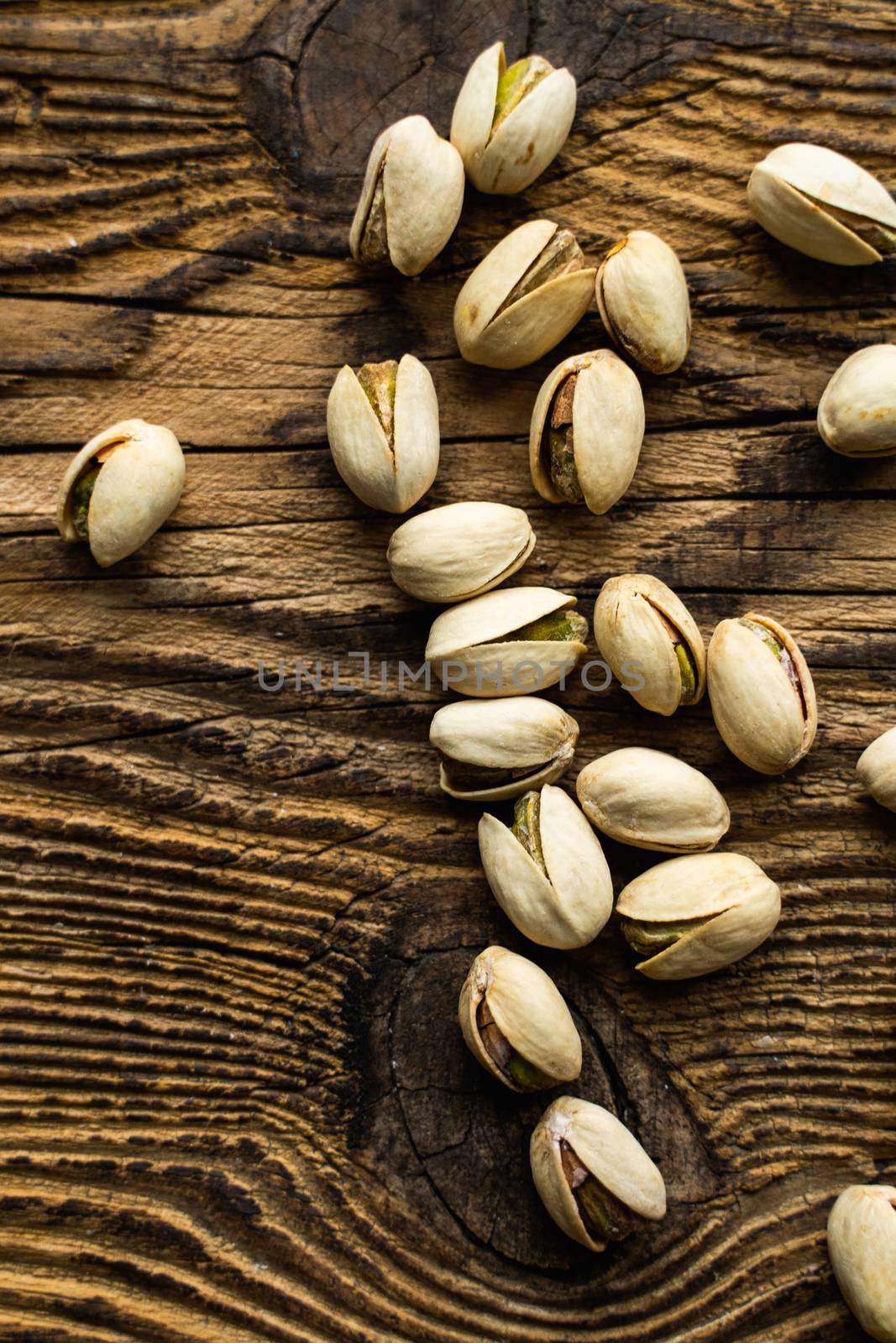 Pistachios scattered on the wooden vintage table. Pistachio is a healthy vegetarian protein nutritious food. Pistachios on rustic old wood