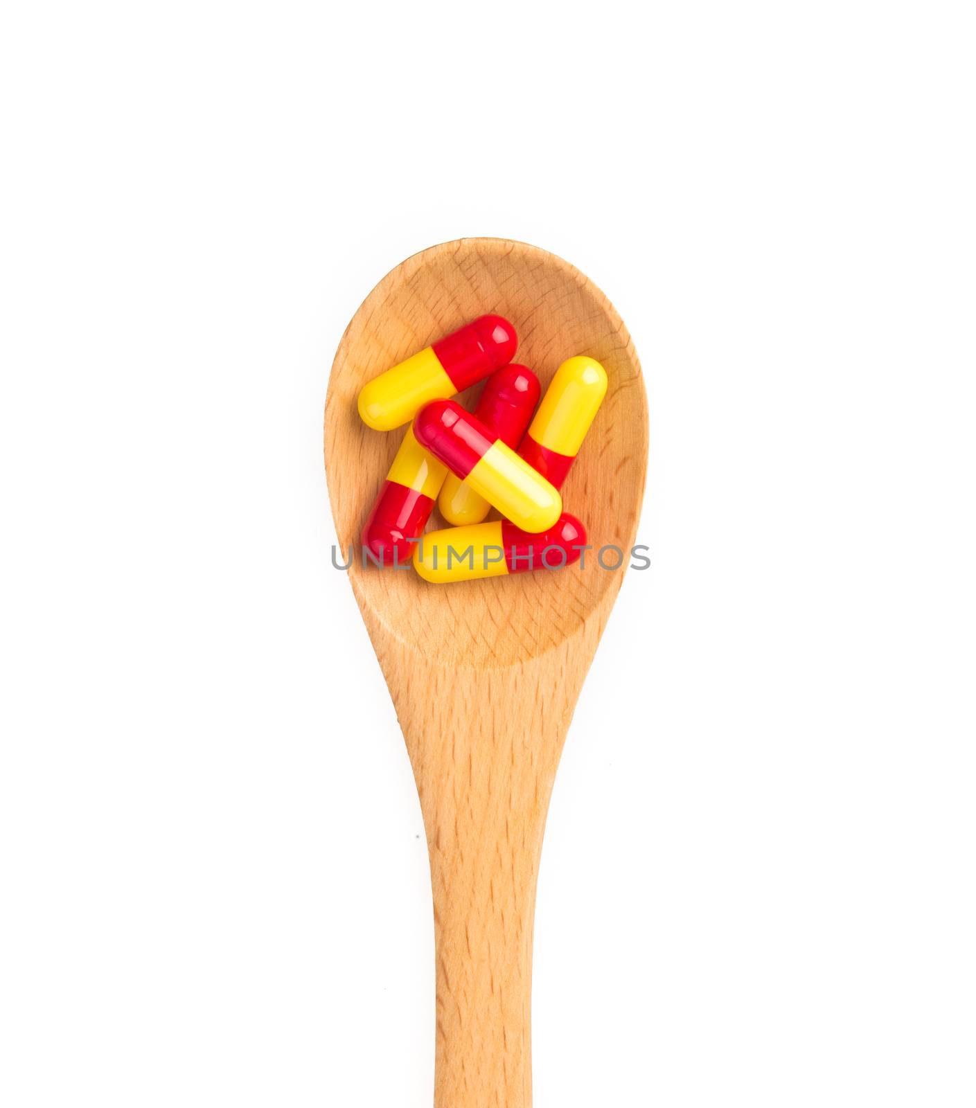 pills in wooden spoon isolated on white background