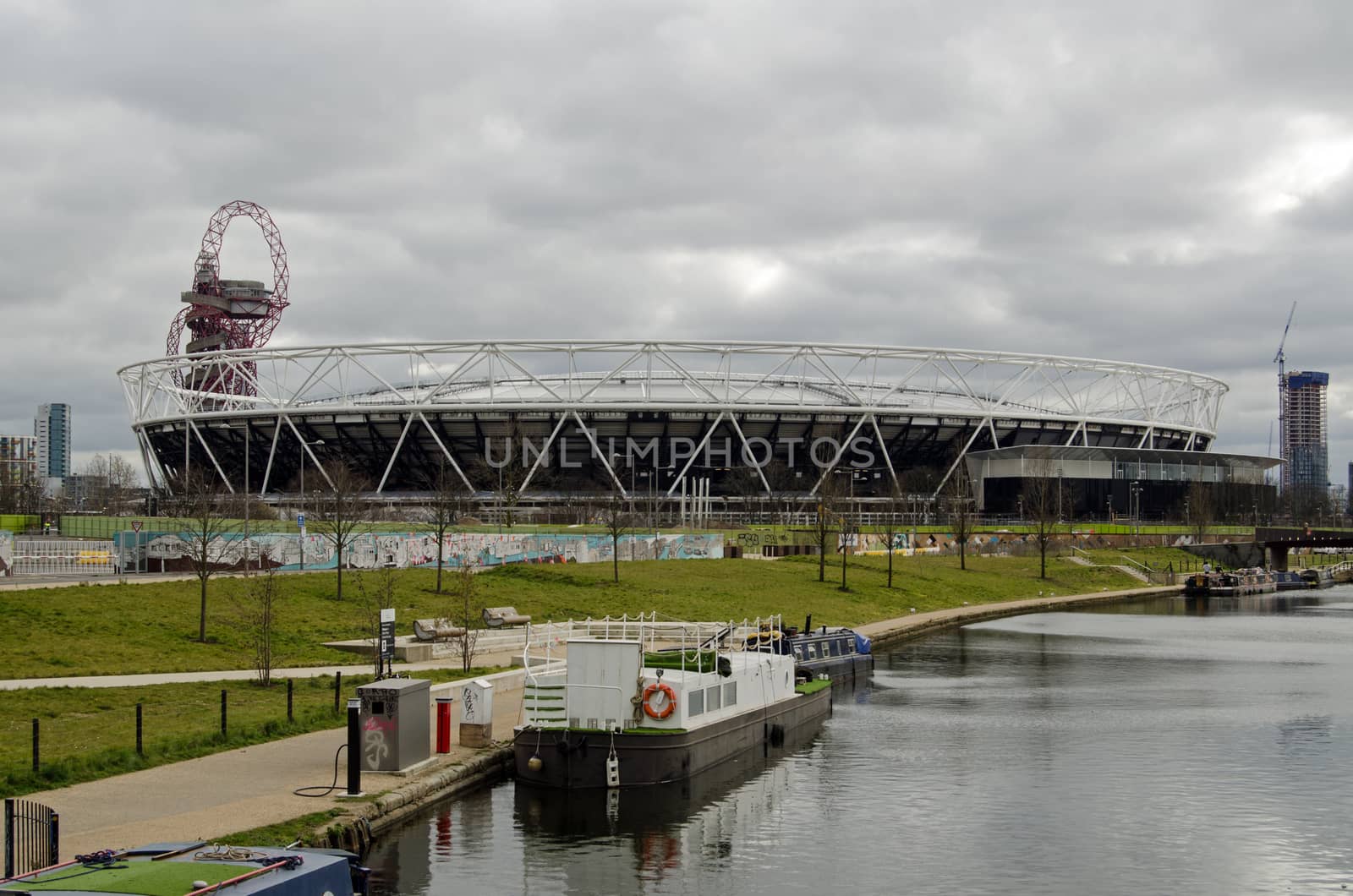 The new West Ham United Stadium in Queen Elizabeth Park, formerly used for the London 2012 Olympics.  With the Orbit tower behind and the Lee Navigation canal on the right.  Cloudy afternoon in March.