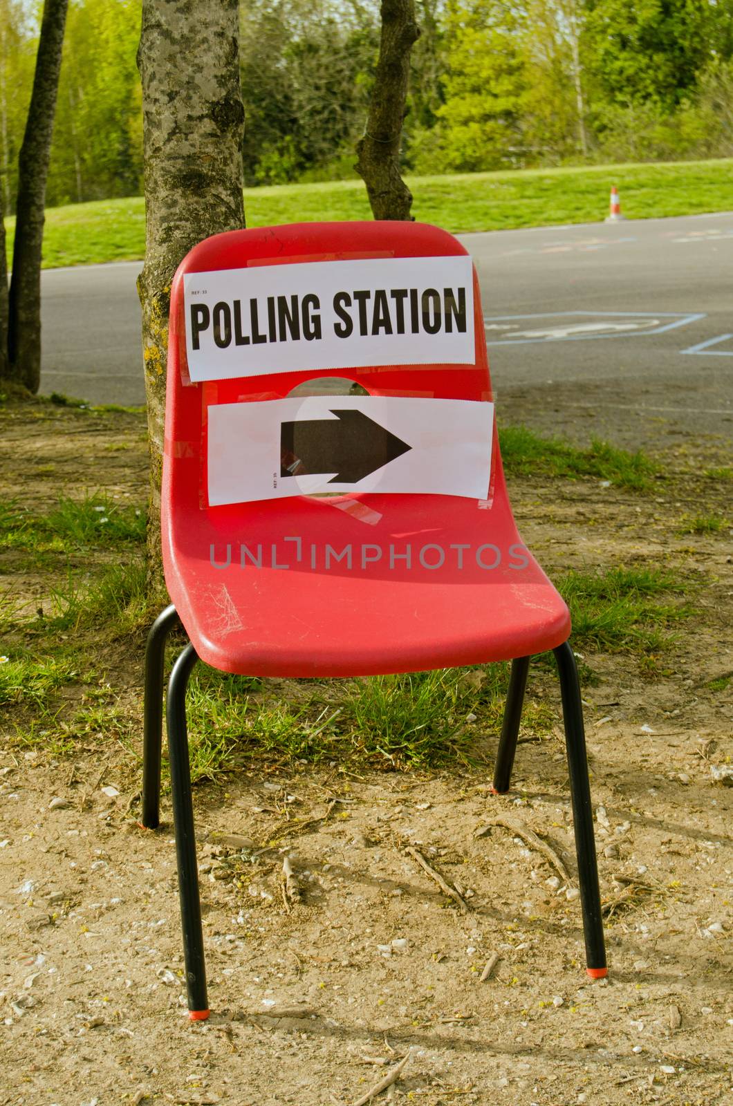 A small child's stacker chair with a sign pointing towards a polling station at a primary school on election day in Basingstoke, Hampshire, UK.