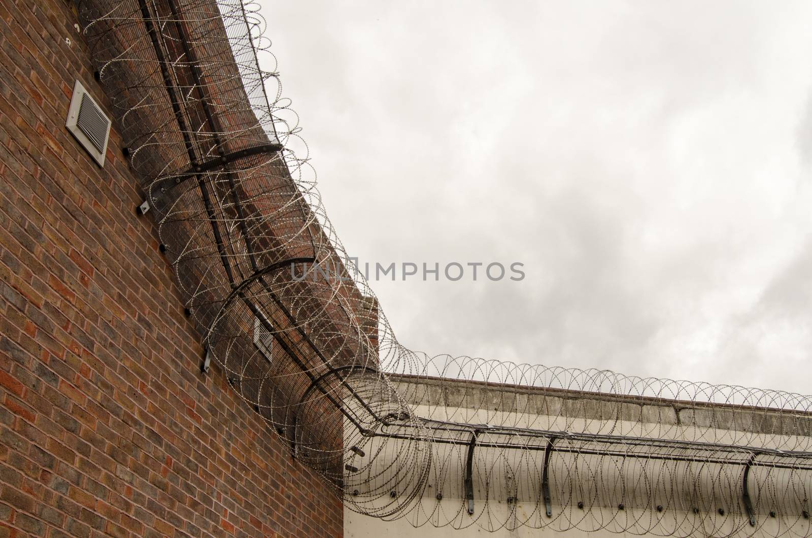 Looking up at the tall wall surrounding Reading Prison with razor wire coiled around the top to deter escape.  Berkshire.  The prison once had playwright Oscar Wilde as an inmate.. 