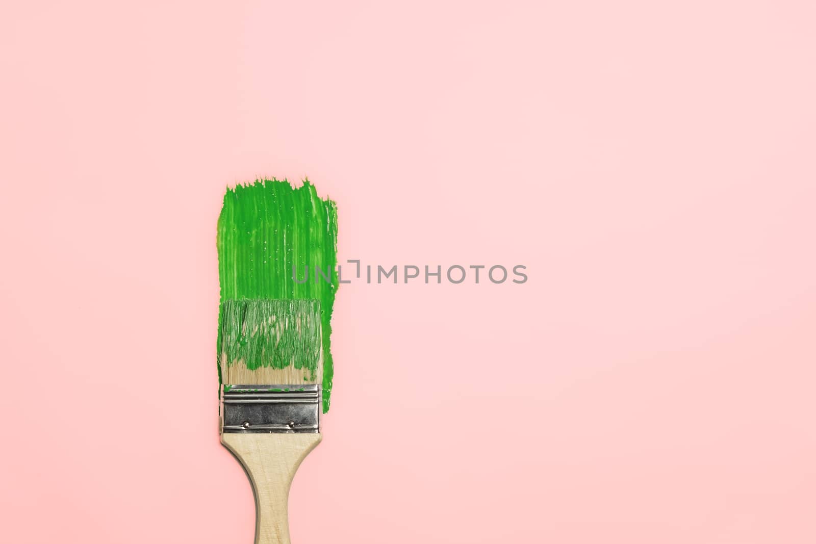 Paintbrush and a trail of green paint in isolated background. Concept of painting, renovation, home and household chores