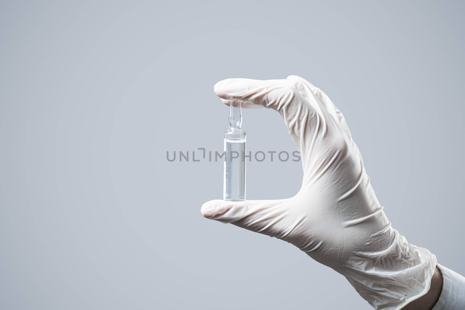 Ampouled solution in a hand wearing glove. by photoboyko