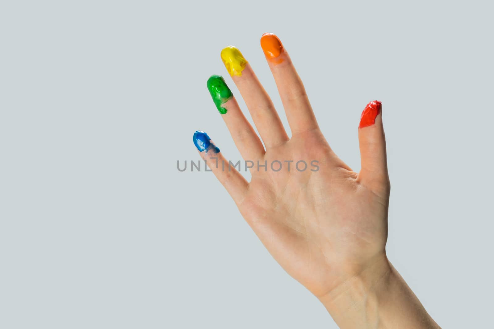 Close-up view of a hand with paint on the fingertips. Blue, green, yellow, orange and red paints on fingers, studio shot.