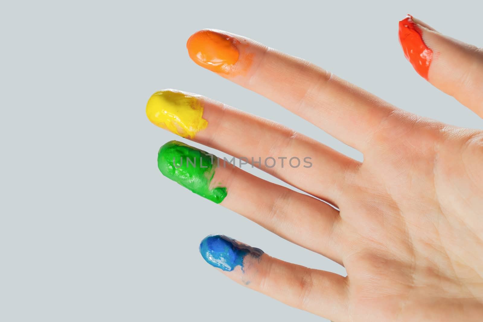 Close-up view of a hand with paint on the fingertips. Blue, green, yellow, orange and red paints on fingers, studio shot.
