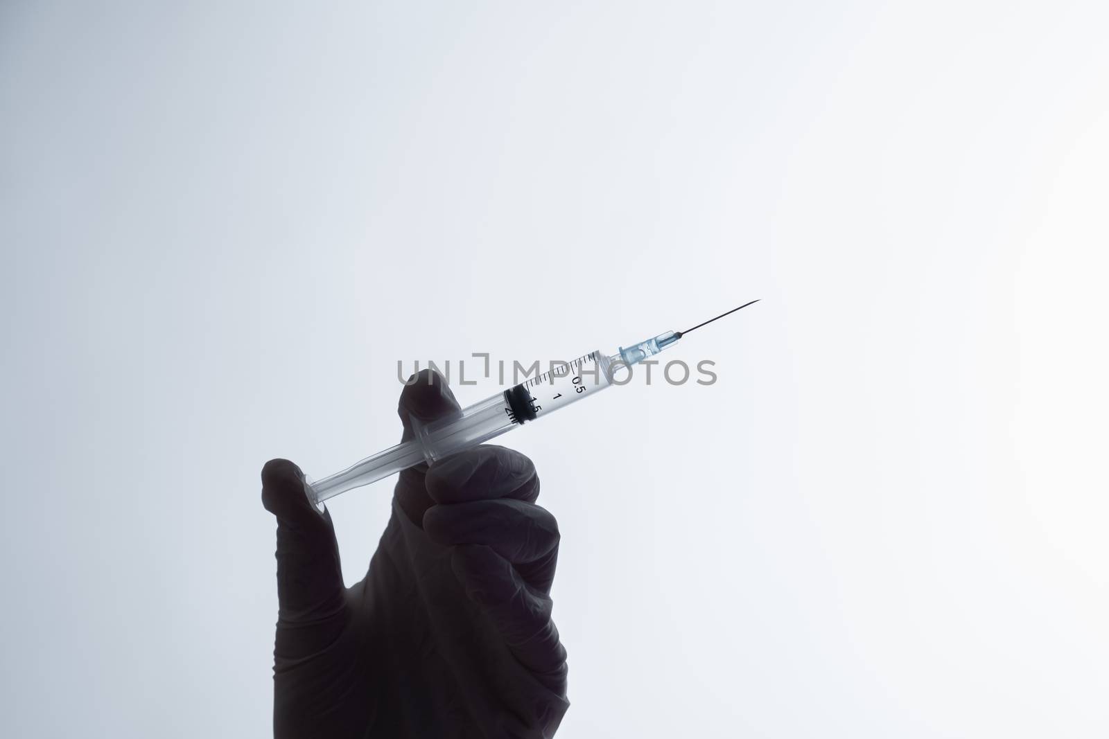 Injection ready for application, dark silhouette on white background. Hand in glove holding a syringe with intravenous injection, concept of vaccination or illegal medicine