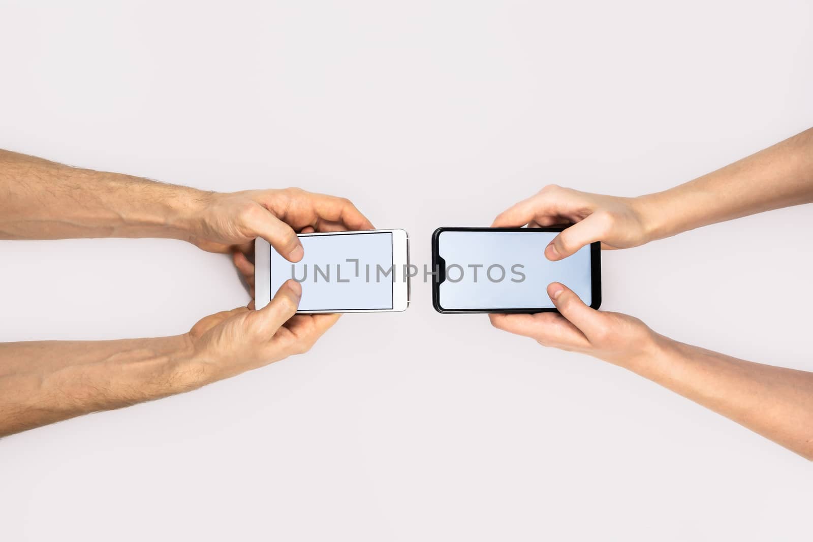 Female and male hands hold smartphones on white background by photoboyko