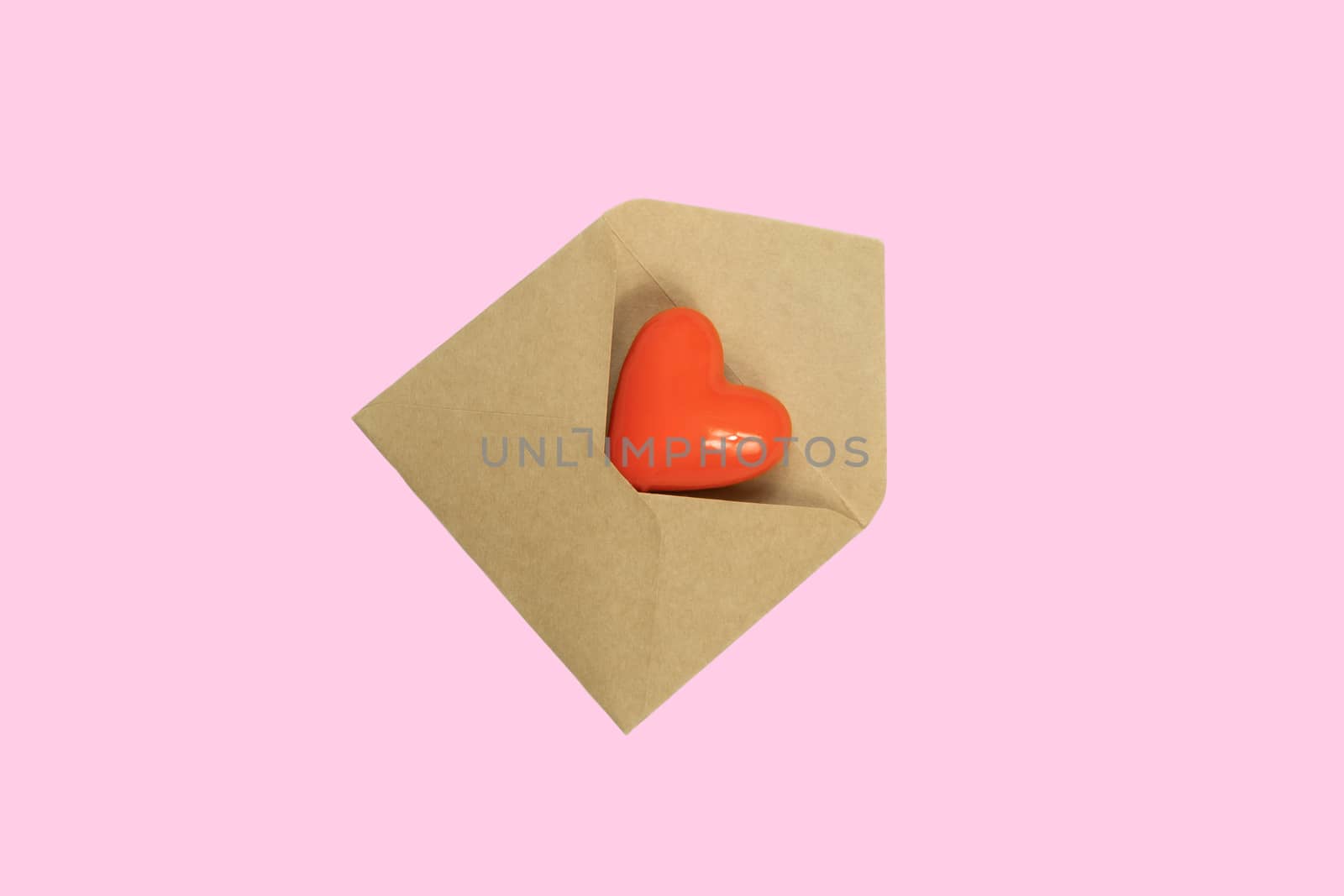 Heart figure in a lteer envelope on pink background, top view. Concept of love correspondence, messaging and relationship in the distance. St. Valentines day concept