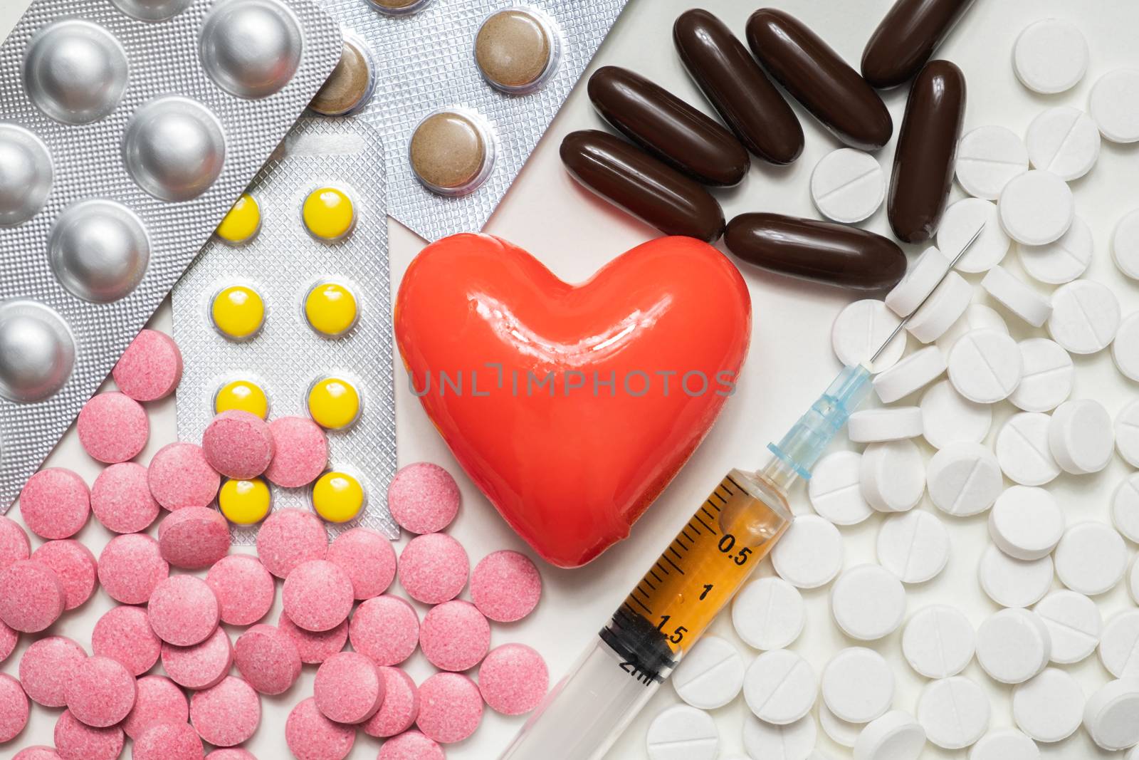 Heart and pills with syringe on white background, top view. Cardiology, heart disease concept.