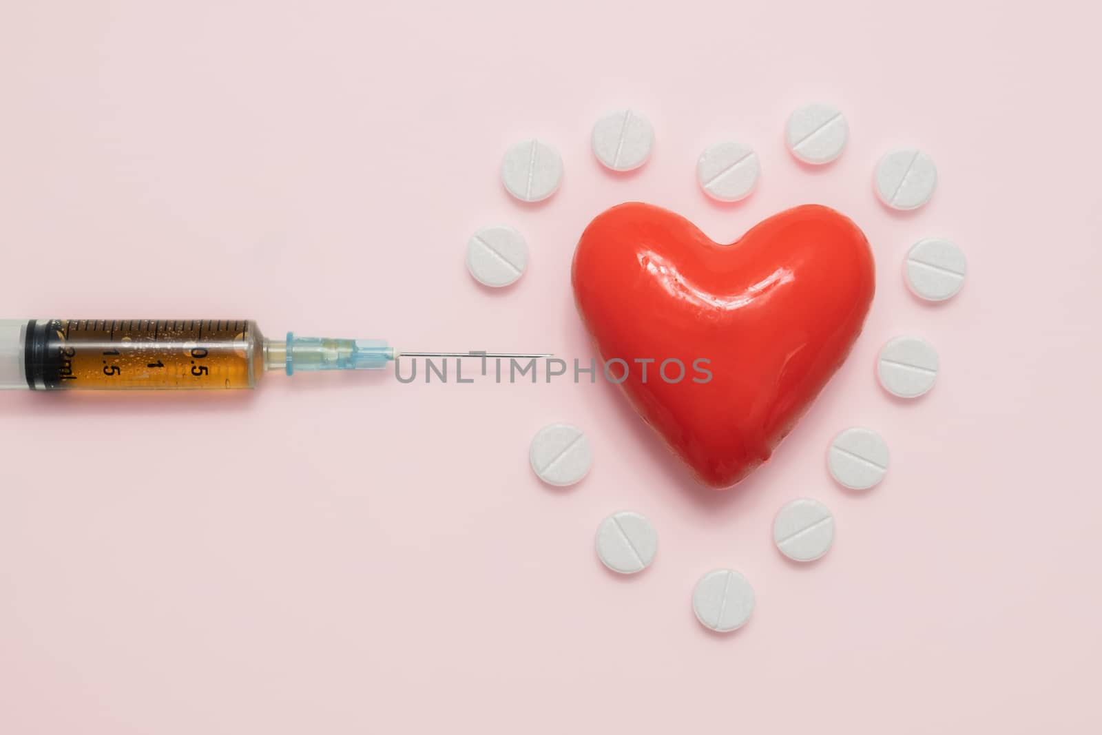 Heart, pills and syringe on pink backround, top view. Cardiology, heart disease concept.