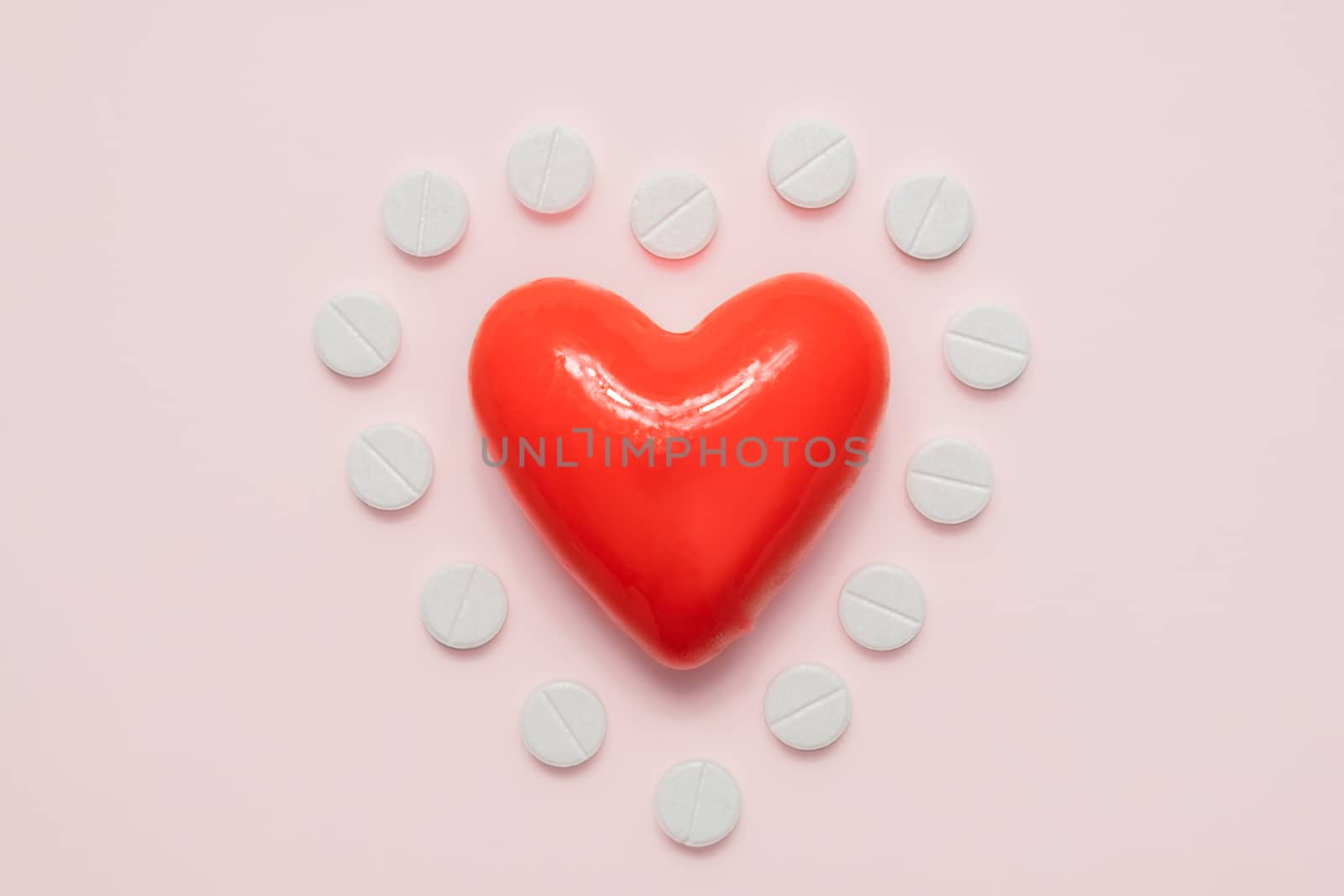 Heart and pills in the shape of a heart on pink background by photoboyko