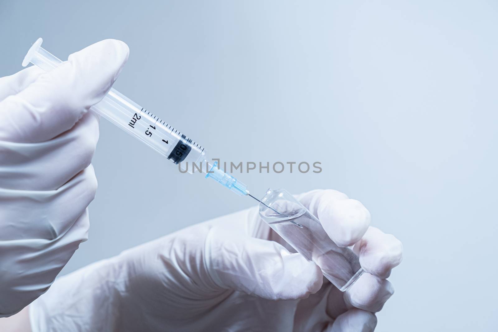 Hands in gloves preparing a medical injection shot. Concept of vaccination, providing medical service or taking a shot in clean laboratory or hospital conditions