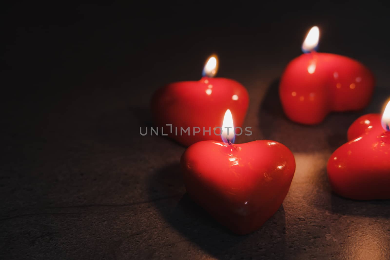 Heart shaped candles burn in the darkness. by photoboyko