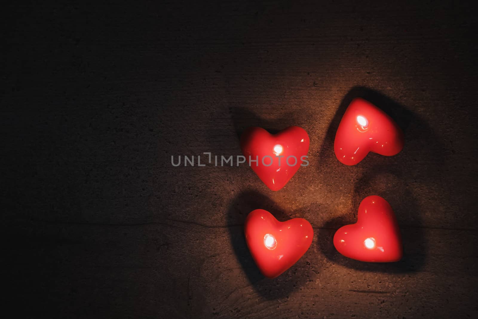 Heart shaped candles burn in the darkness, top view with copy space. Concept of the Saint Valentine's Day