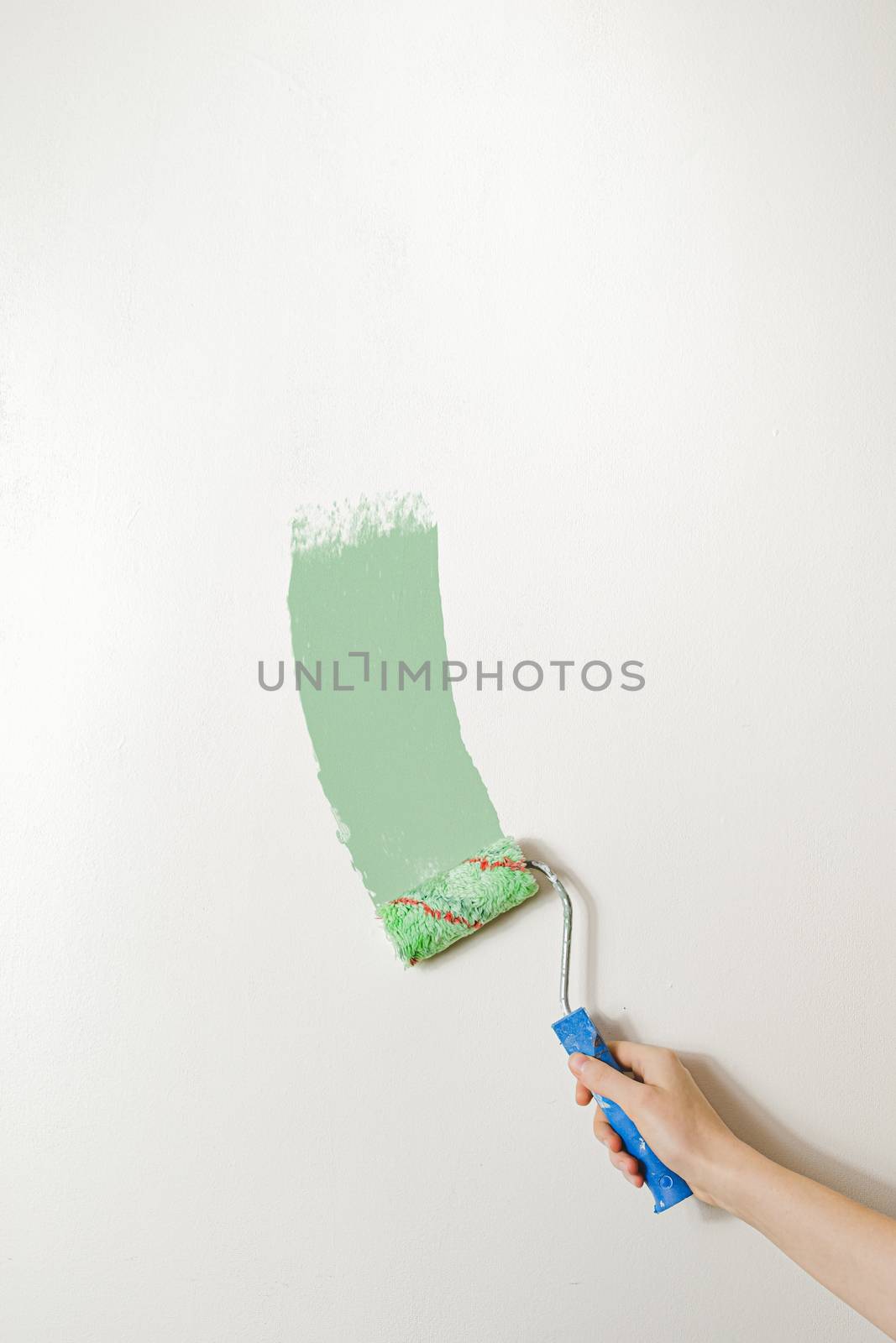 Hand with a paintbrush against the white wall. by photoboyko