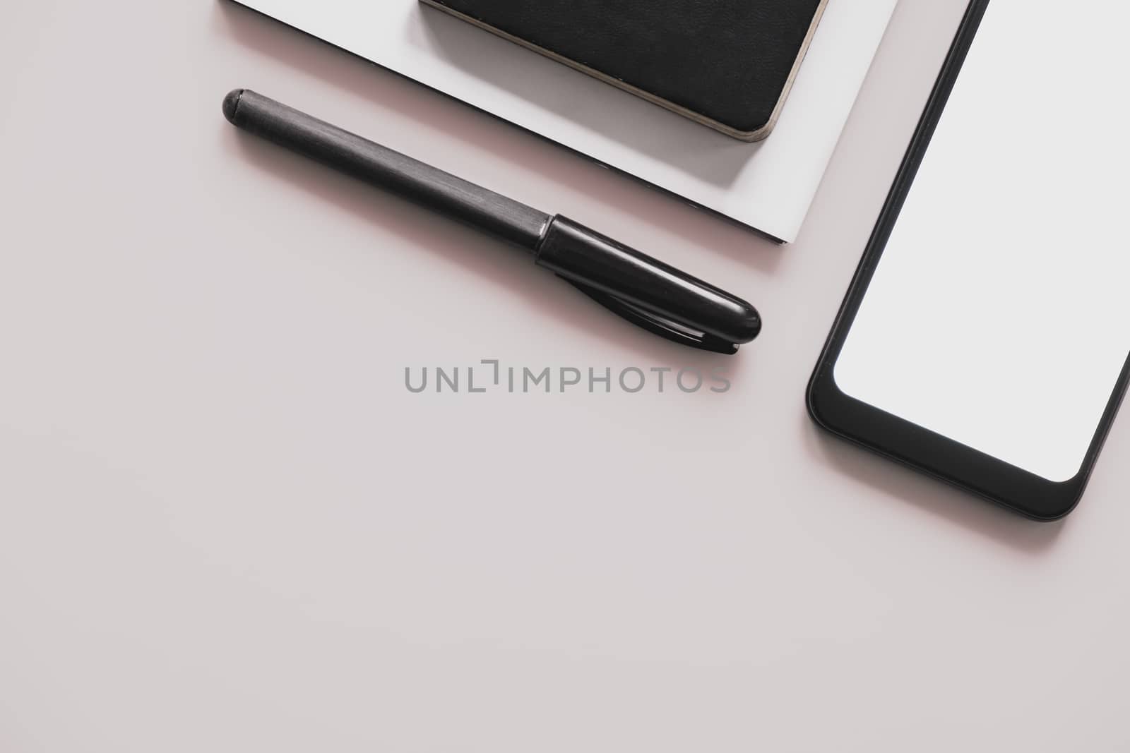 Business flat lay on pastel background with copy space. Smartphone, writing pen and notebook organizer on minimalistic background