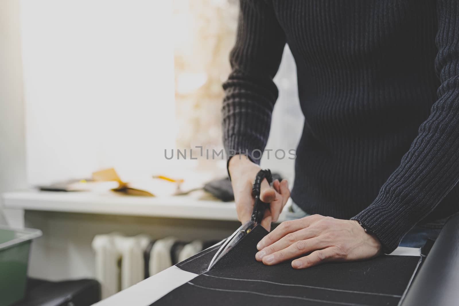 Hands of a male worker cut fabric with large scissors. Hand labor, handcrafting goods, doing small business