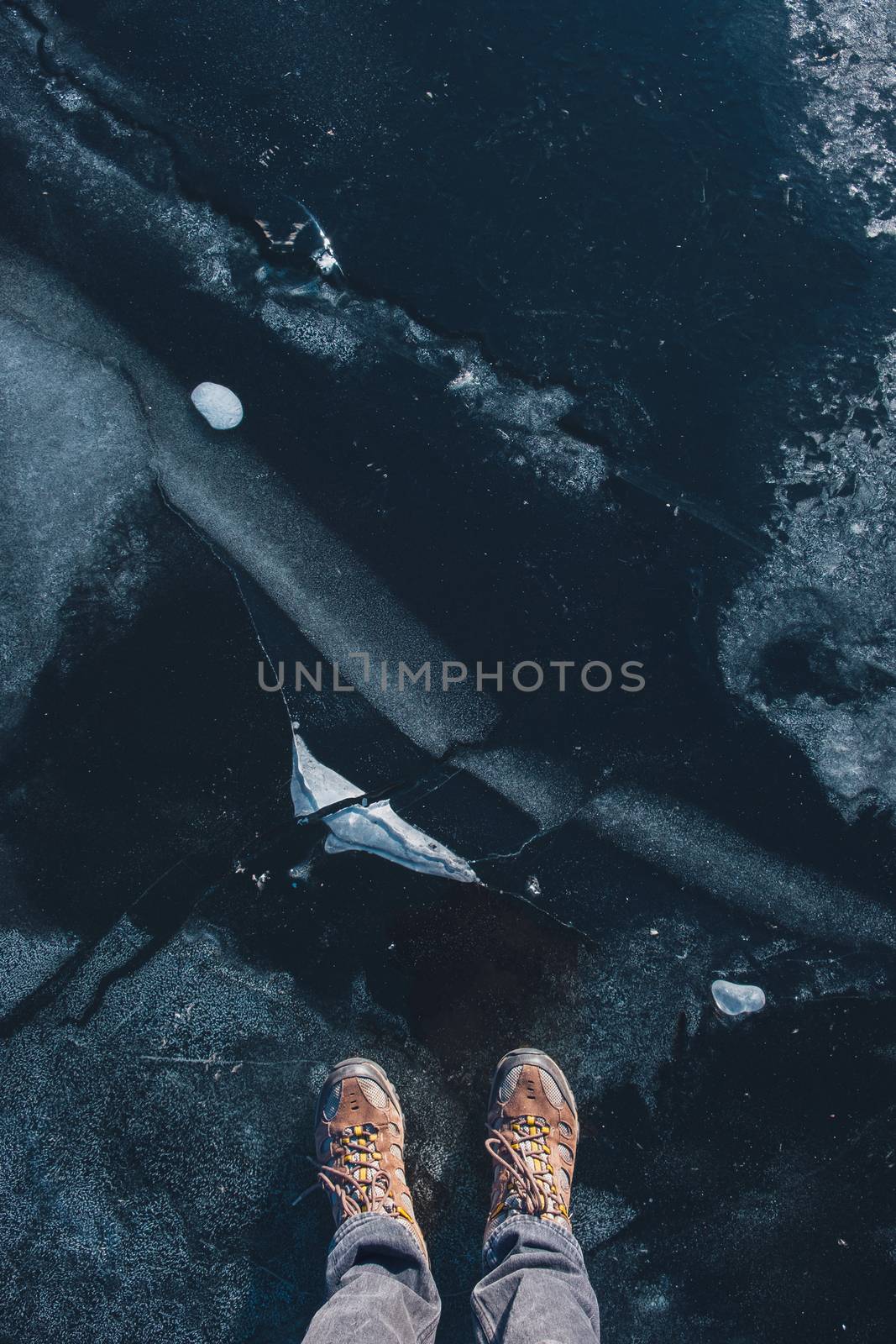 Ice texture, top view with human feet. Standing on beautiful ice,  point of view shot, blue tint