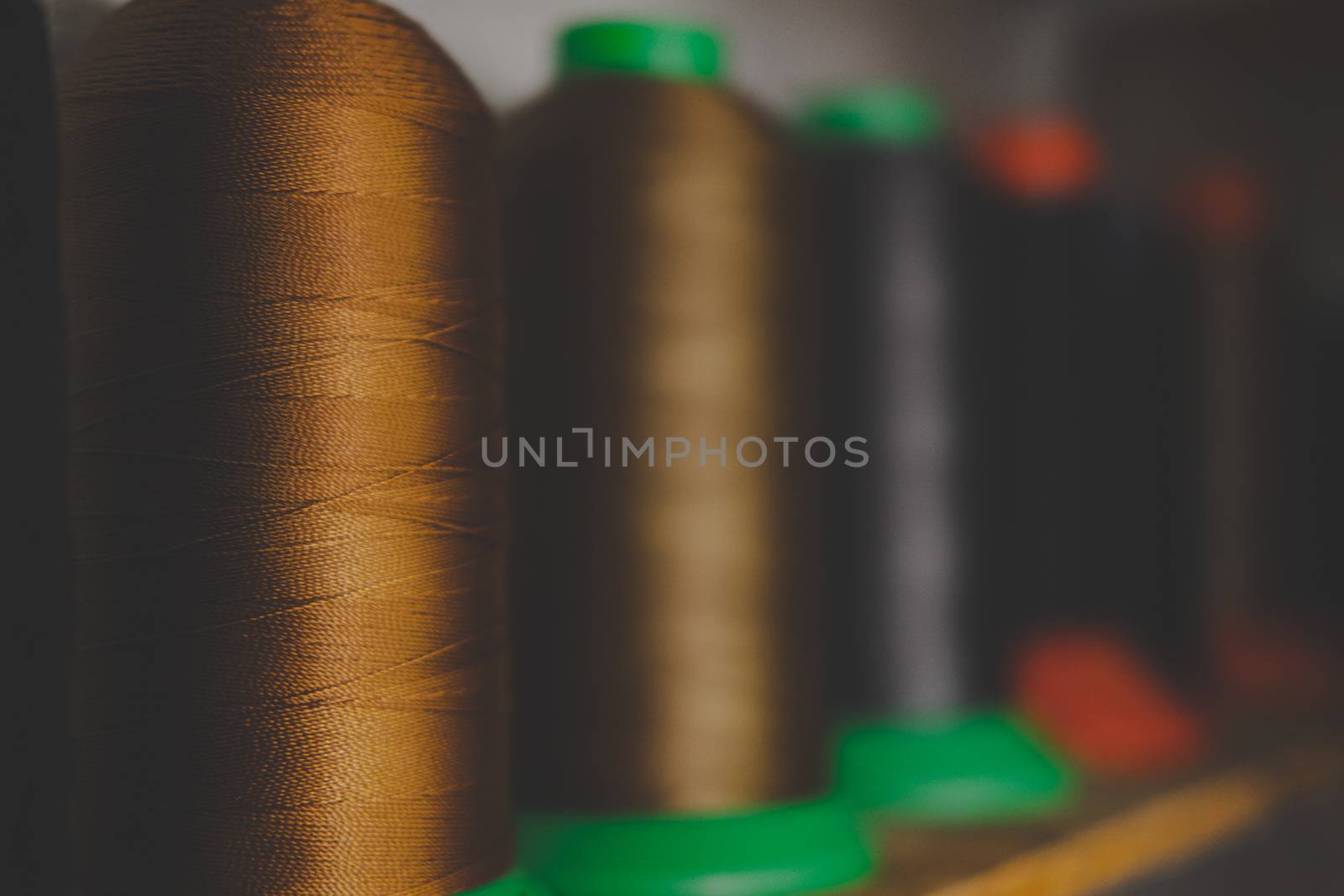 Rolls of gold and black threads, low-key image. Shallow depth of field, stocks of sewing threads