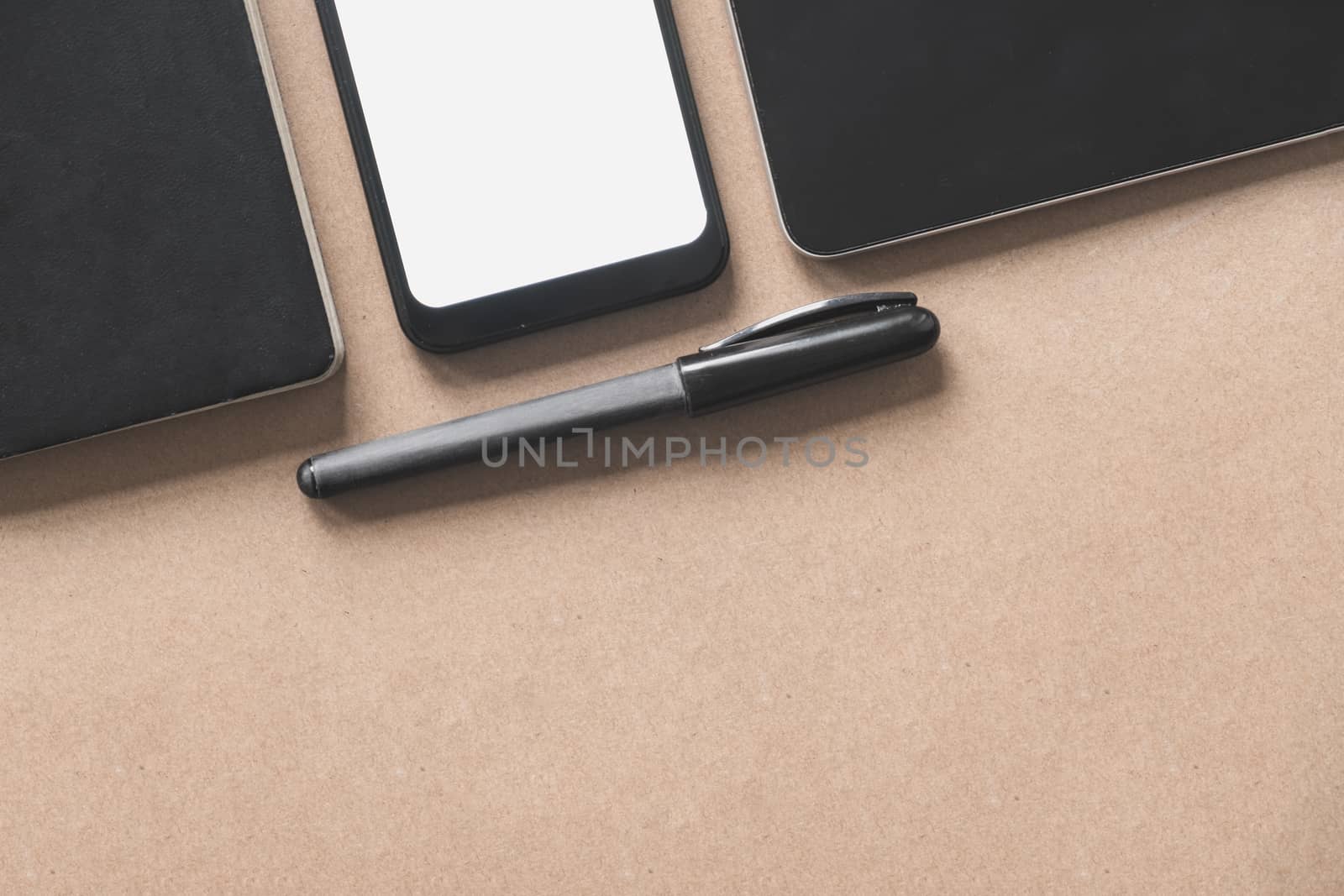 Business flat lay on brown paper background. Smartphone, tablet computer and notebook organizer on vintage background