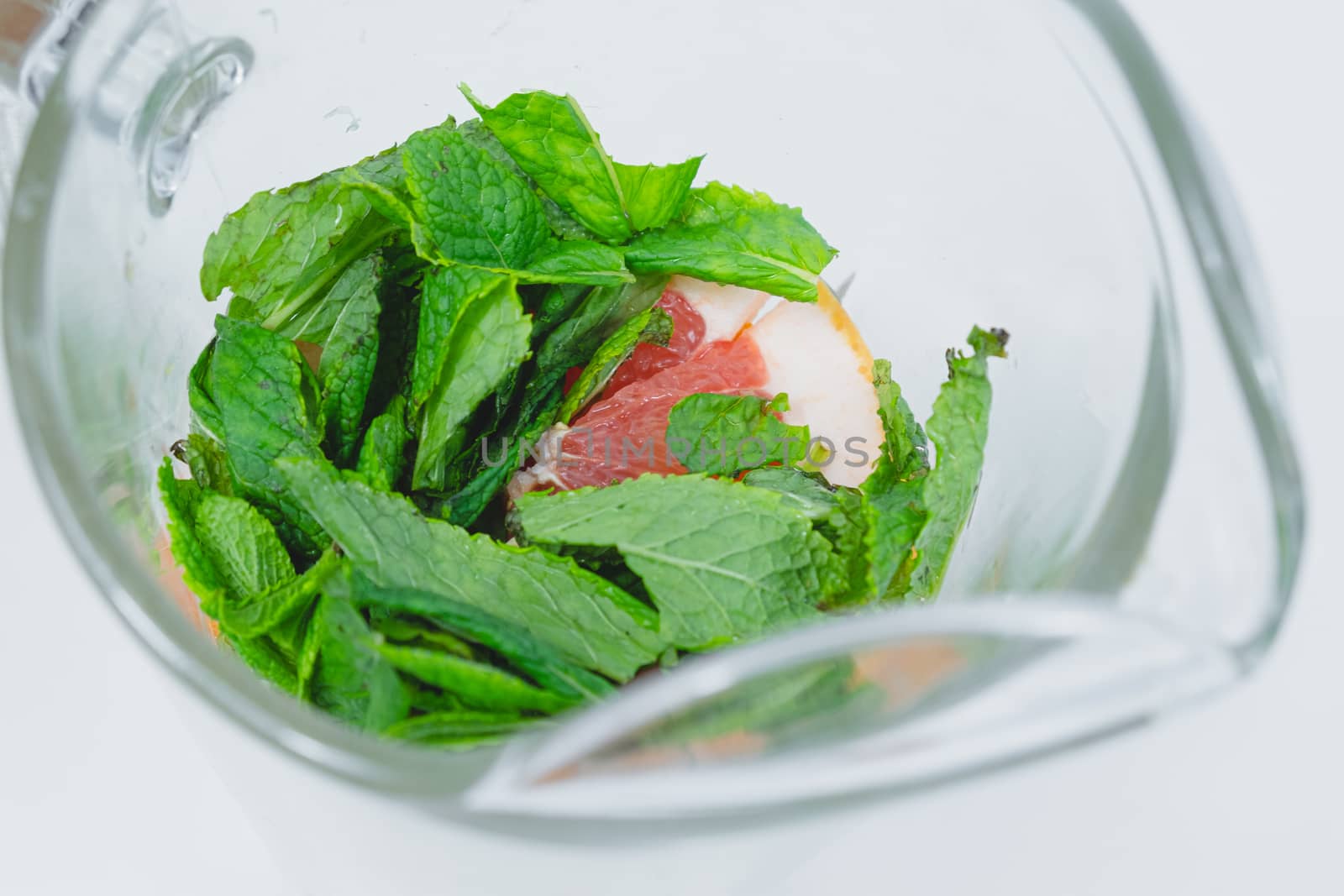 Fresh peppermint leaves and grapefruit slices in a glass, close-up view. Preparing tonic water or lemonade, healthy fresh drink concept