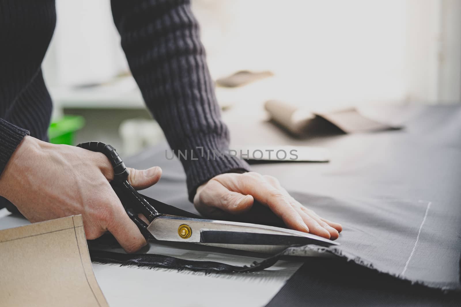 Hands of a male worker cut fabric with large scissors. by photoboyko