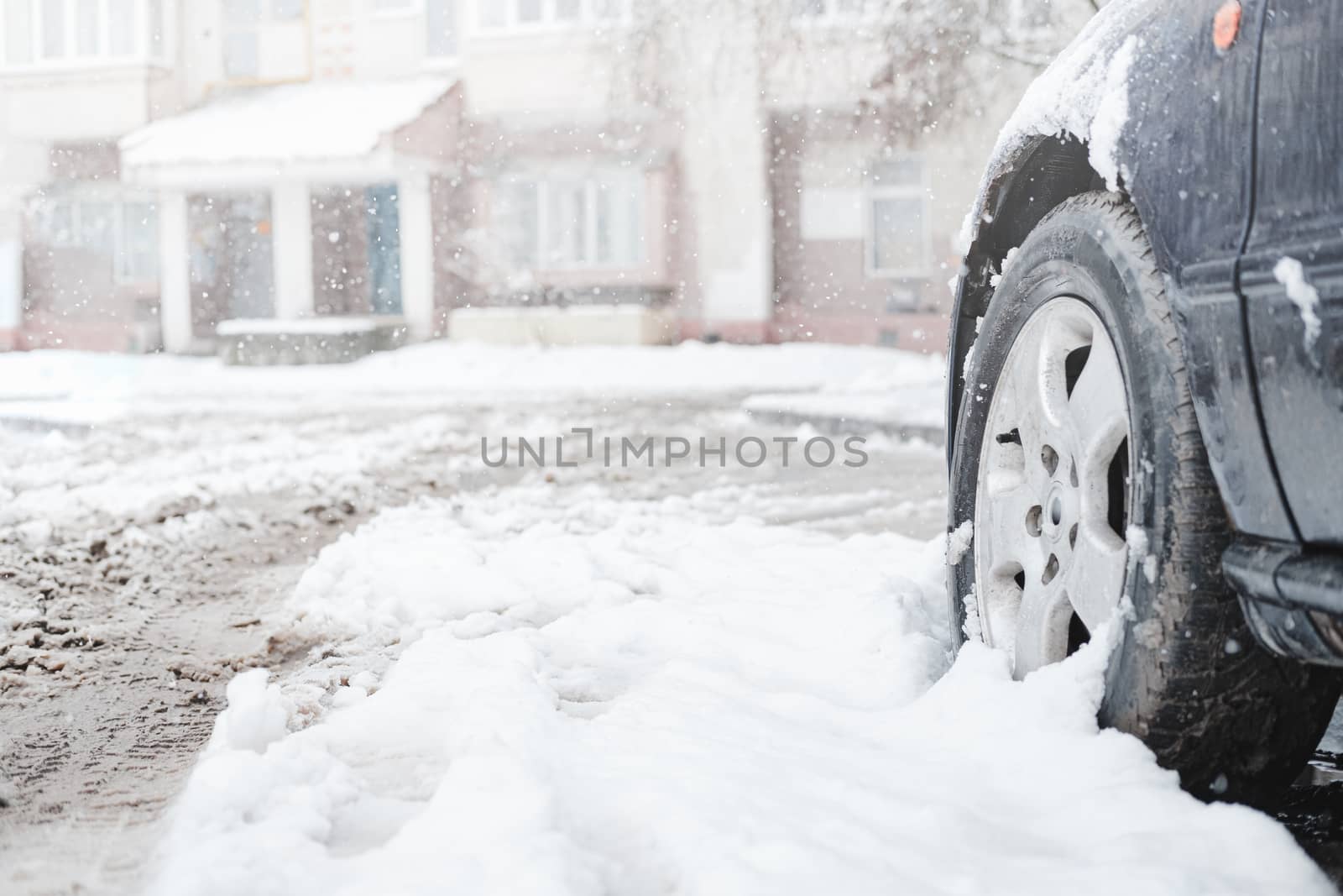 The wheel of a car among wet snow. Traffic, commuting problems caused by the storm in winter