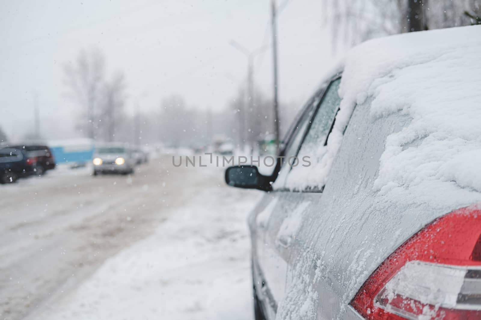 A vehicle covered in snow on the road. Slow traffic in winter storm, road filled with wet snow
