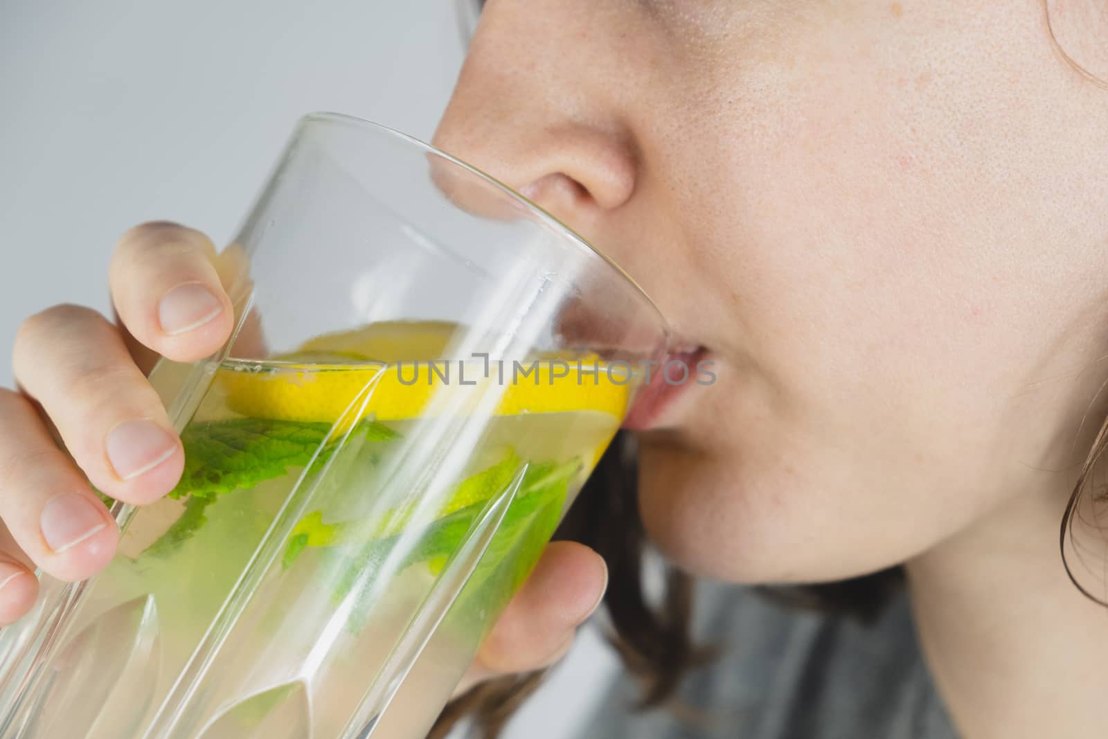 Glass of lemon drink in a human hand. Hangover cure, tonic water or mojito refreshment