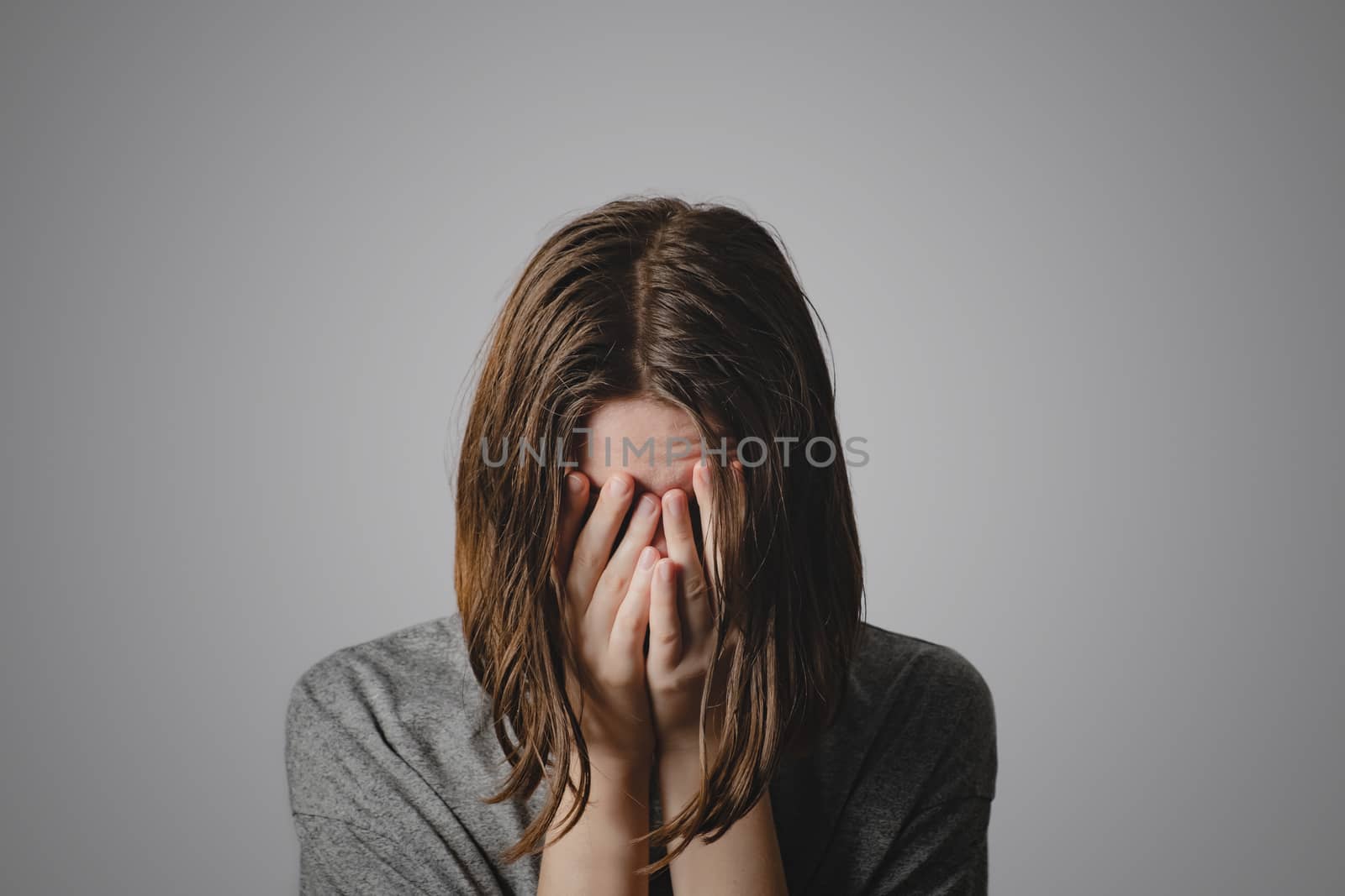 Woman covers face in hands. Concept of despair, depression, loss by photoboyko