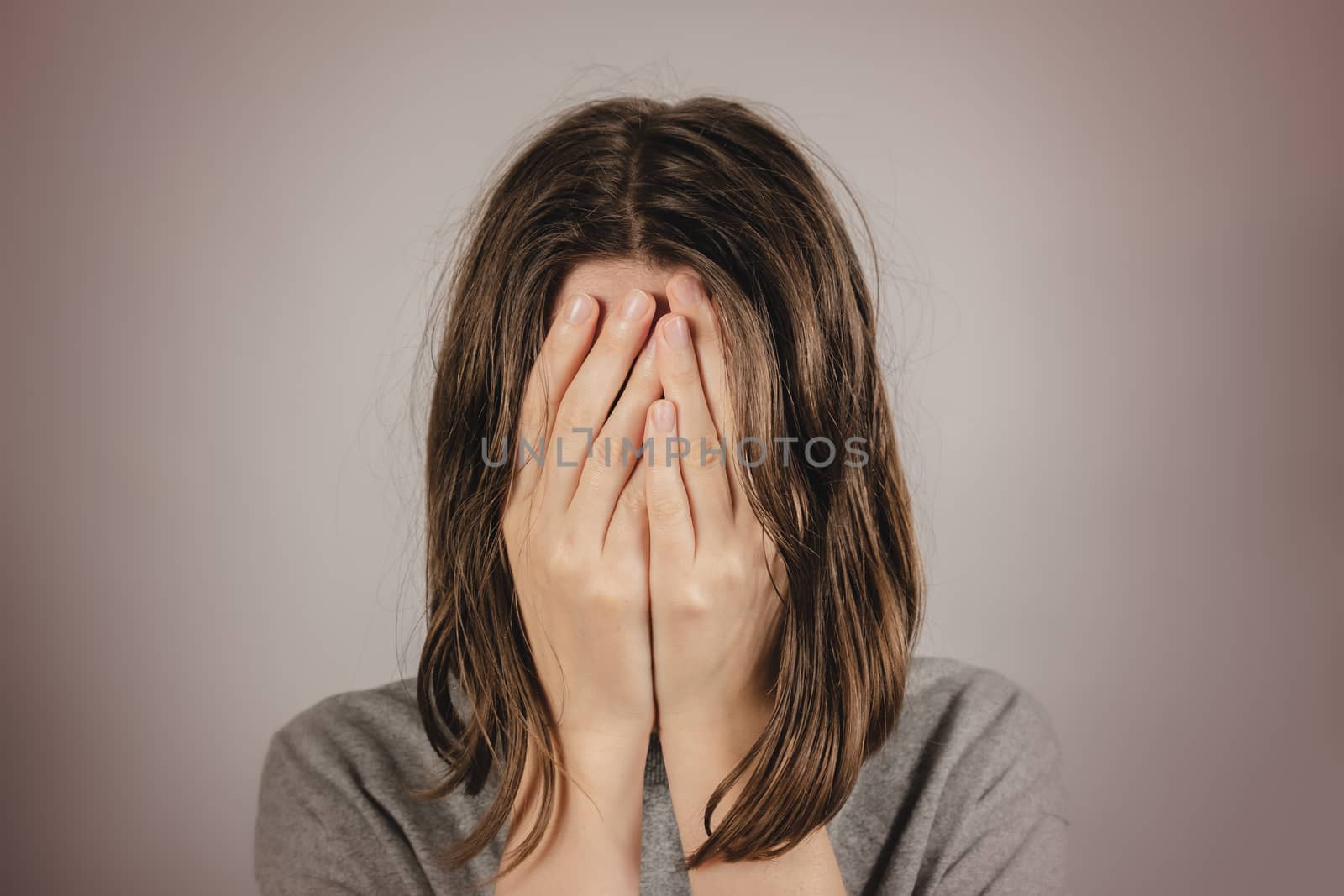 Woman covers face in hands. Concept of despair, depression, loss by photoboyko