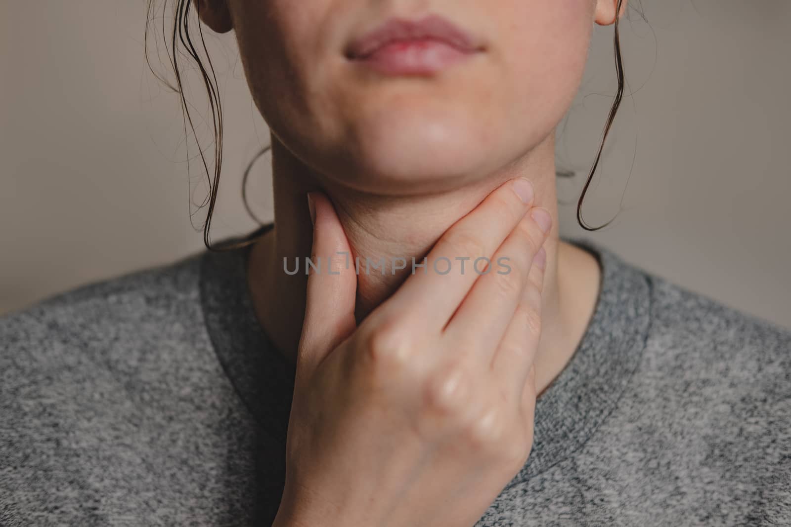 Sore throat, virus disease or flu. Woman holds hand against her throat feeling pain