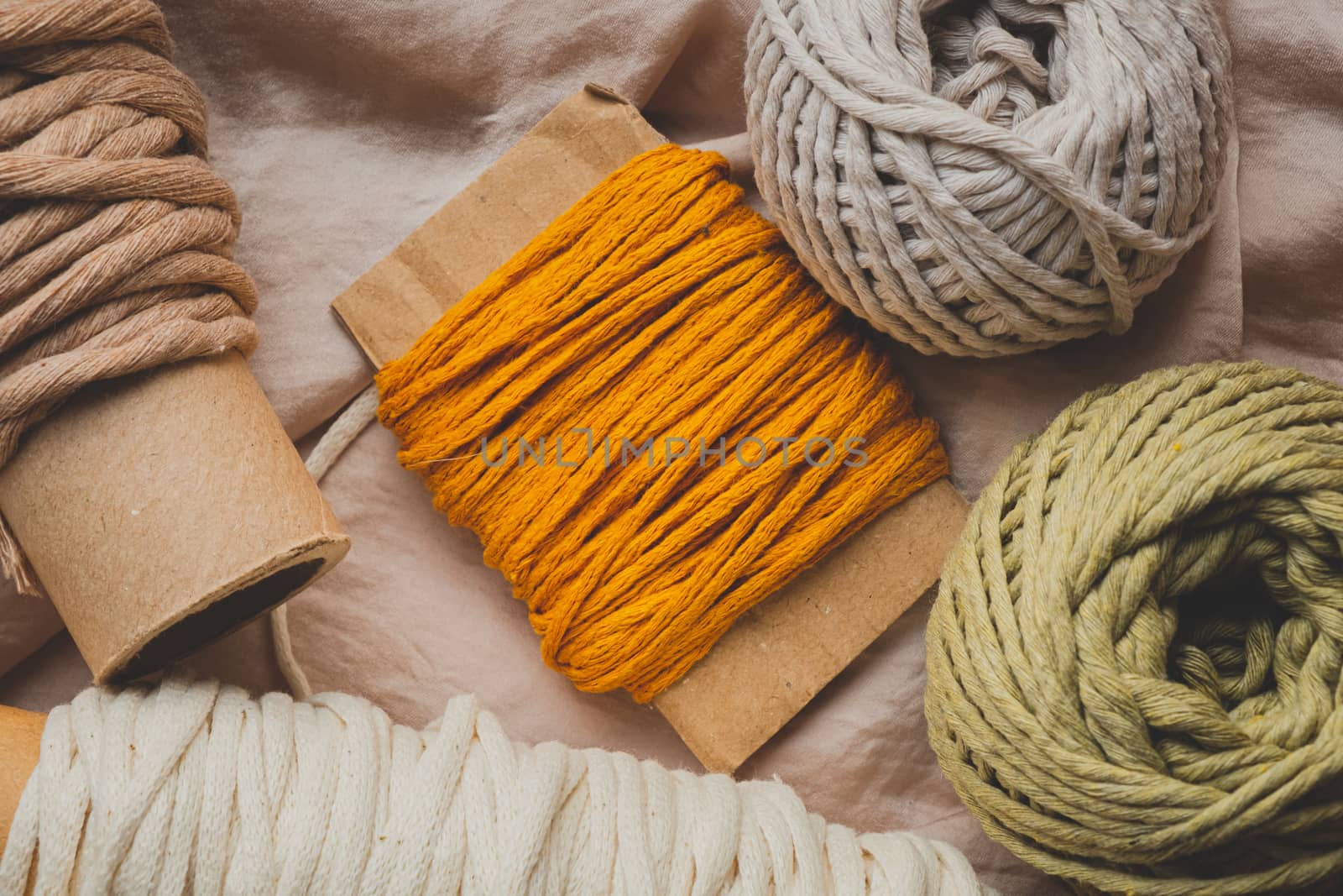 Macrame ropes in various colors, top view. Mustard, red, olive and white crochet threads in beautiful pastel backdrop, flat lay image