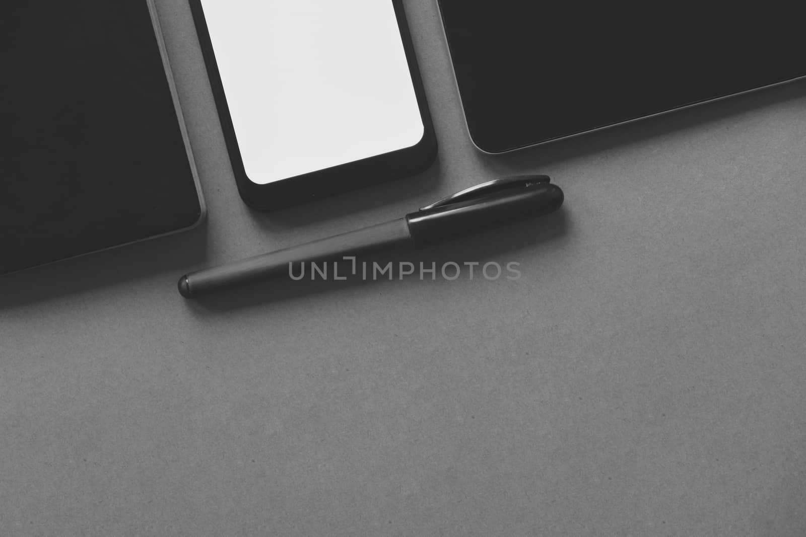 Business flat lay on brown paper background. Smartphone, tablet computer and notebook organizer on dark monochrome background